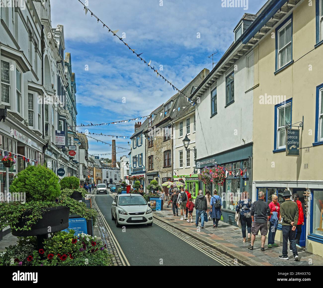Flower tubs and bunting bring a celebratory feel to Southside Street on Plymouth’s historic Barbican. A quirky mix of small shops, public houses and r Stock Photo