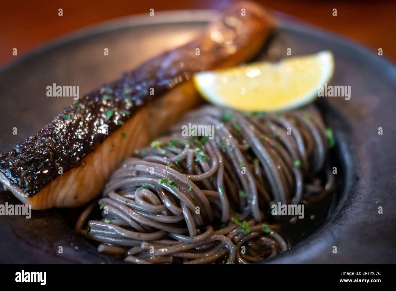 Cold soba noodle with pan seared salmon served on plate with lemon