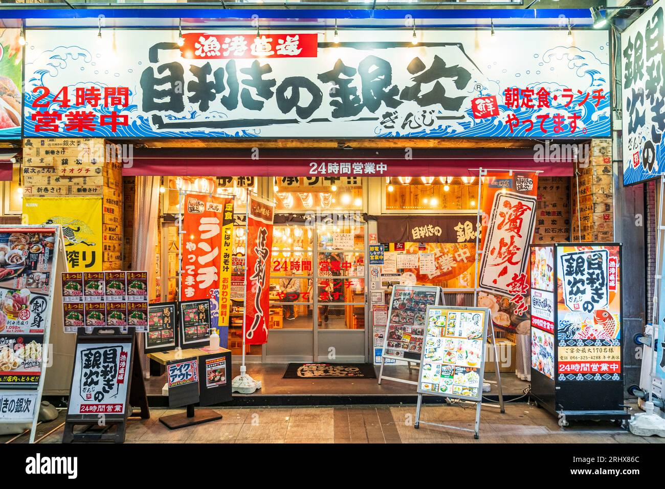 Front facade and entrance of a branch of the popular Mekiki no Ginza seafood chain restaurant in Shimotori shopping arcade in Kumamoto in the evening. Stock Photo