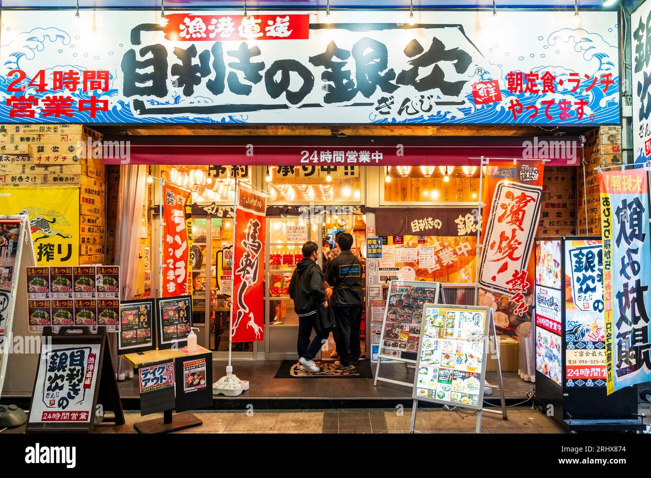 Front facade and entrance of a branch of the popular Mekiki no Ginza seafood chain restaurant in Shimotori shopping arcade in Kumamoto in the evening. Stock Photo