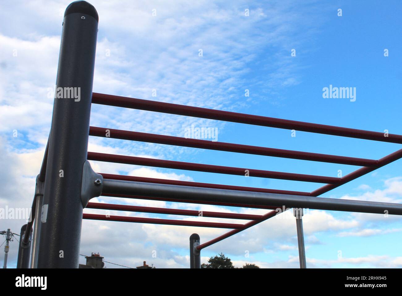 A photo of red monkey bars against a blue sky. Stock Photo