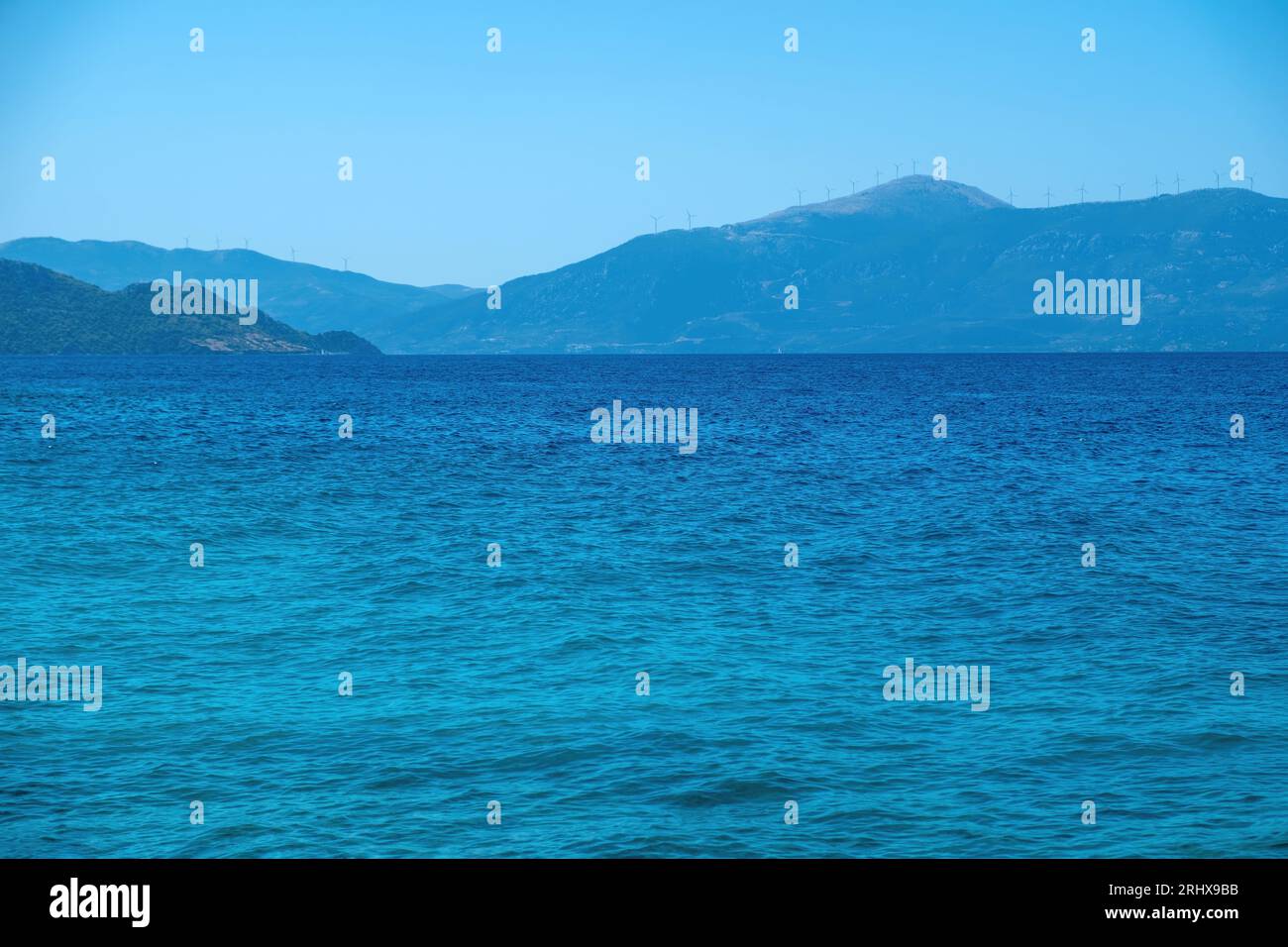Sea landscape background. Vast Mediterranean wavy sea water under clear Greek blue sky, mountain, island, summer destination, space. Stock Photo
