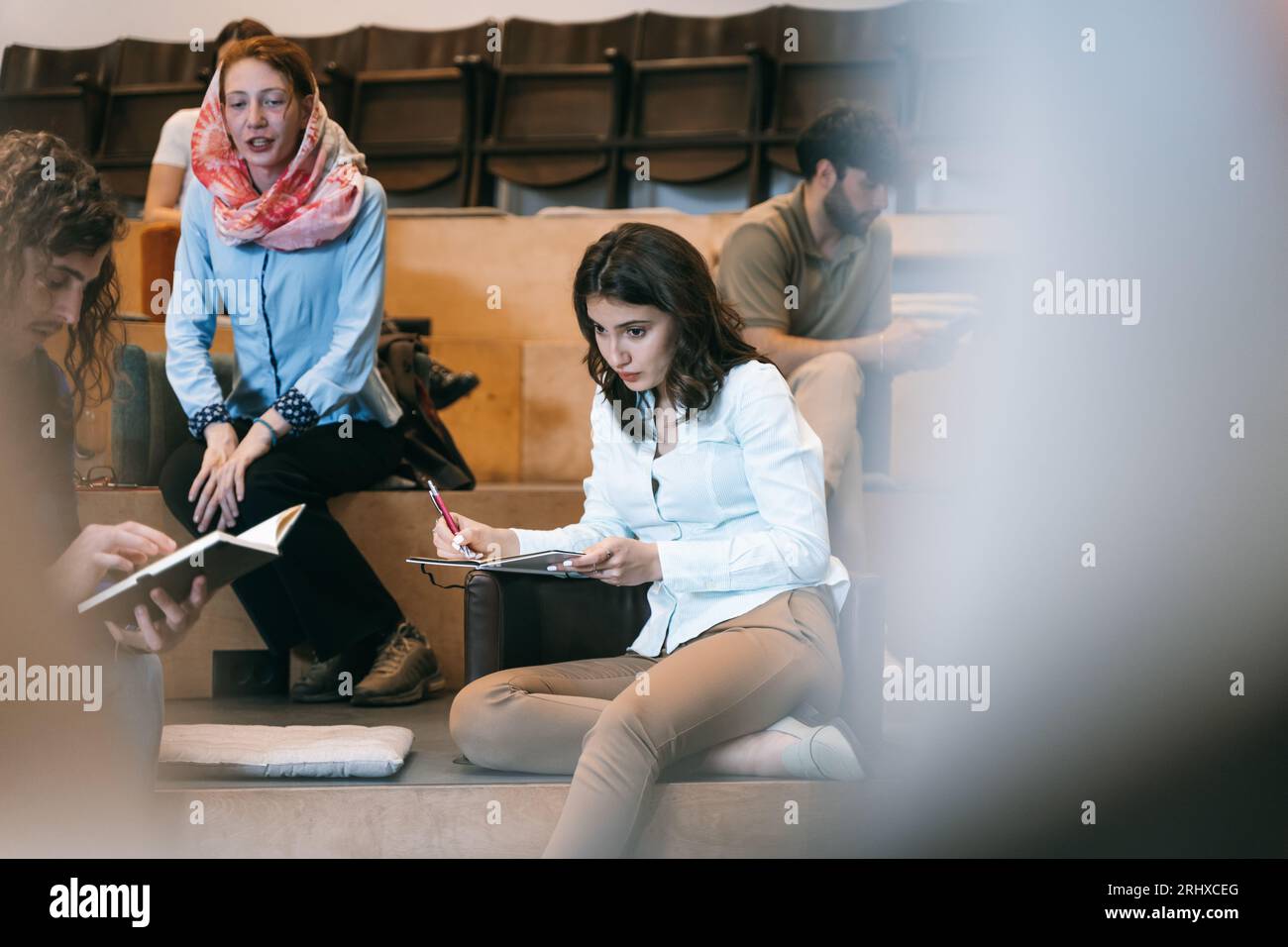 Alluring female employee thinking before she writes down in a notebook Stock Photo