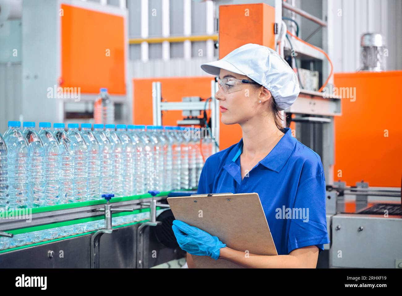 Water Bottle Process Control Bottling factory worker inspecting quality of water bottles before ...