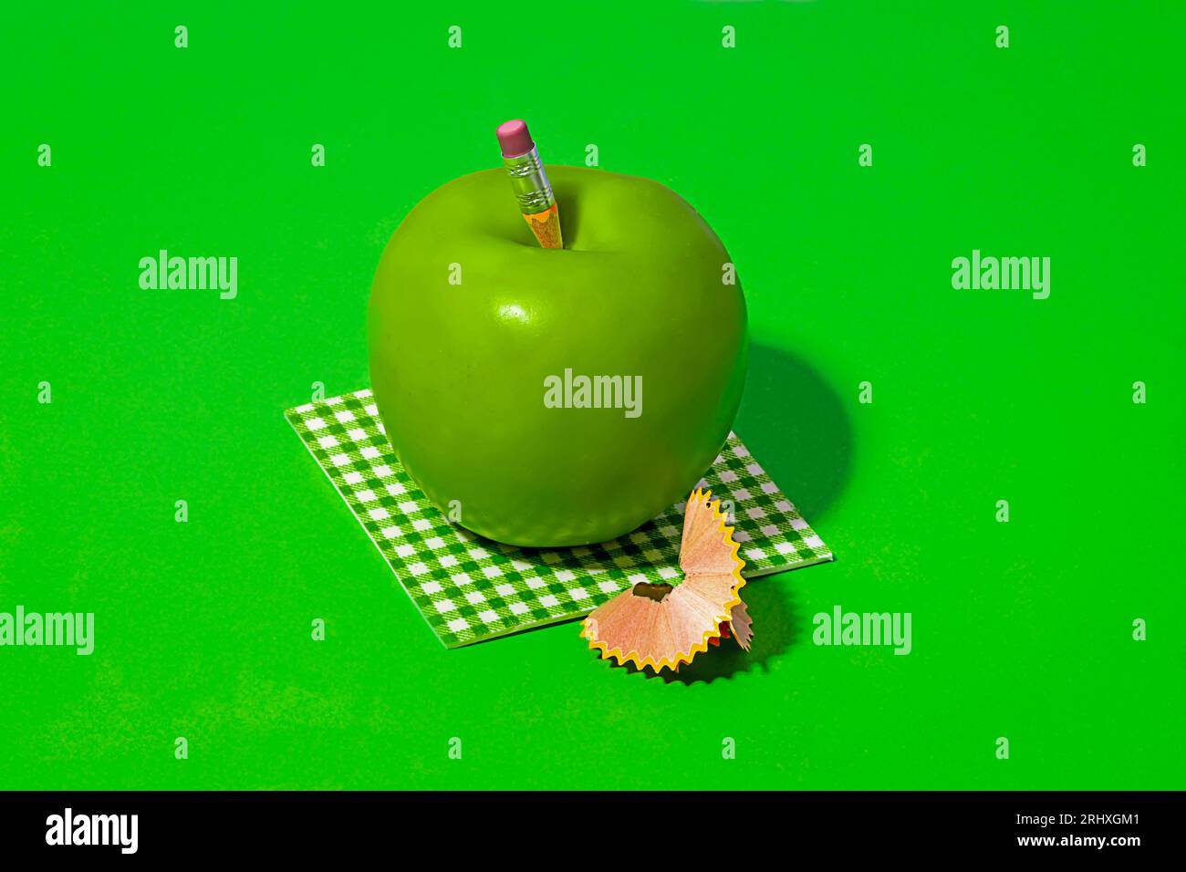 Pencil on healthy Granny Smith apple placed on check pattern cloth near pencil shavings on