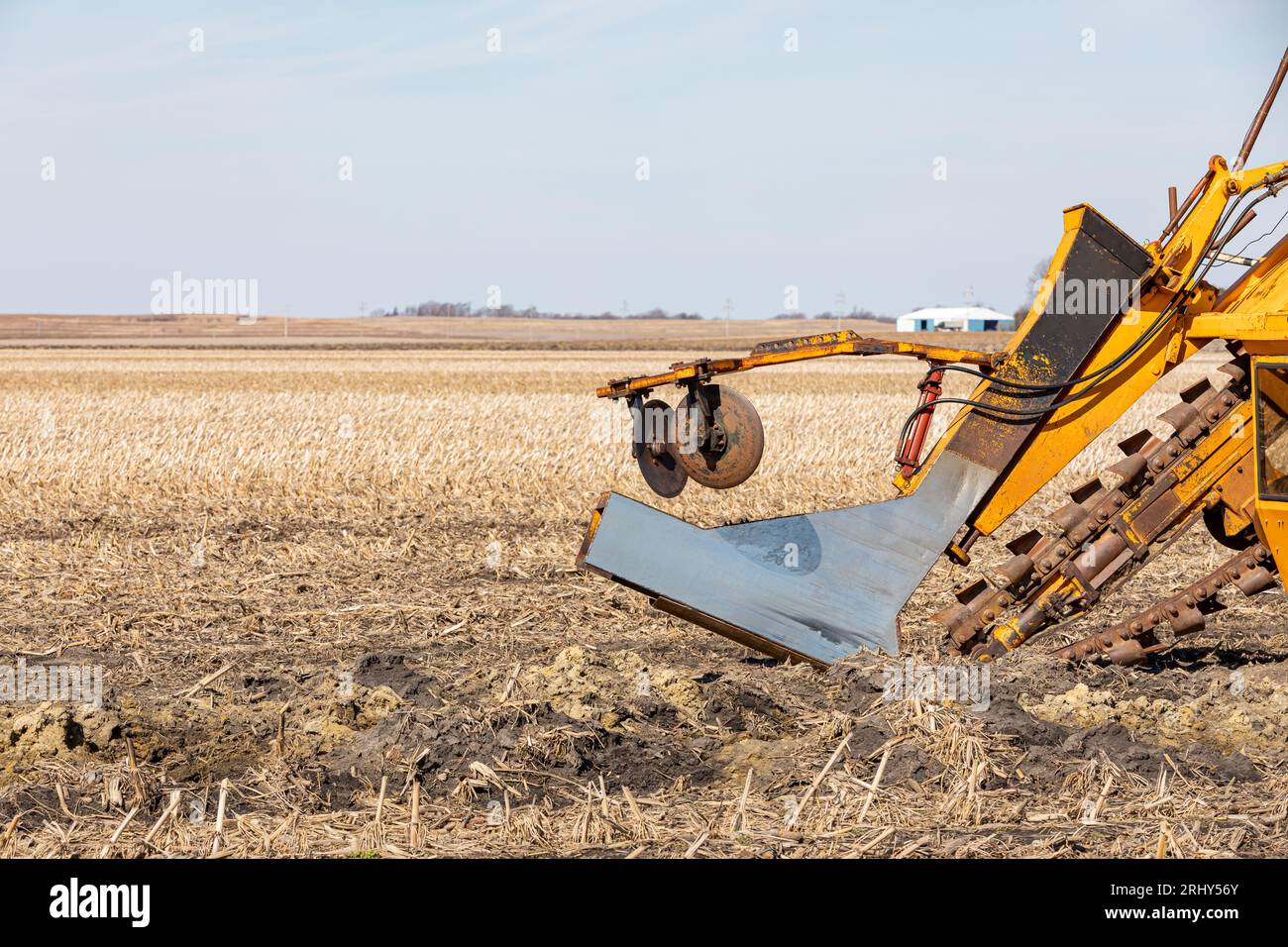 Field tile plow machine in farm field. Water drainage, soil conservation and agriculture flooding control concept Stock Photo