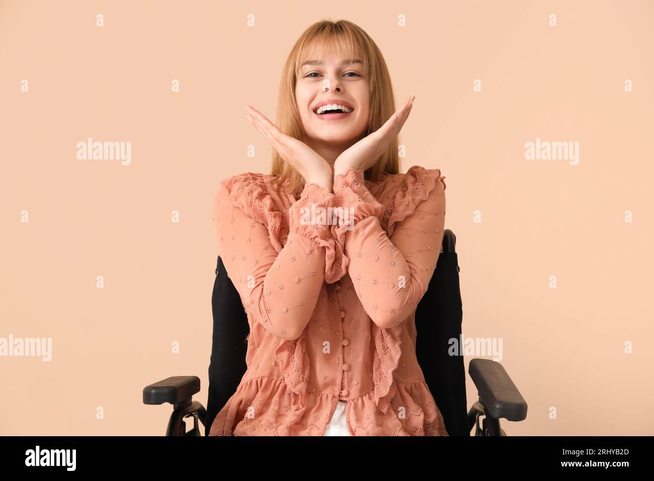 Happy young woman in wheelchair on beige background Stock Photo - Alamy