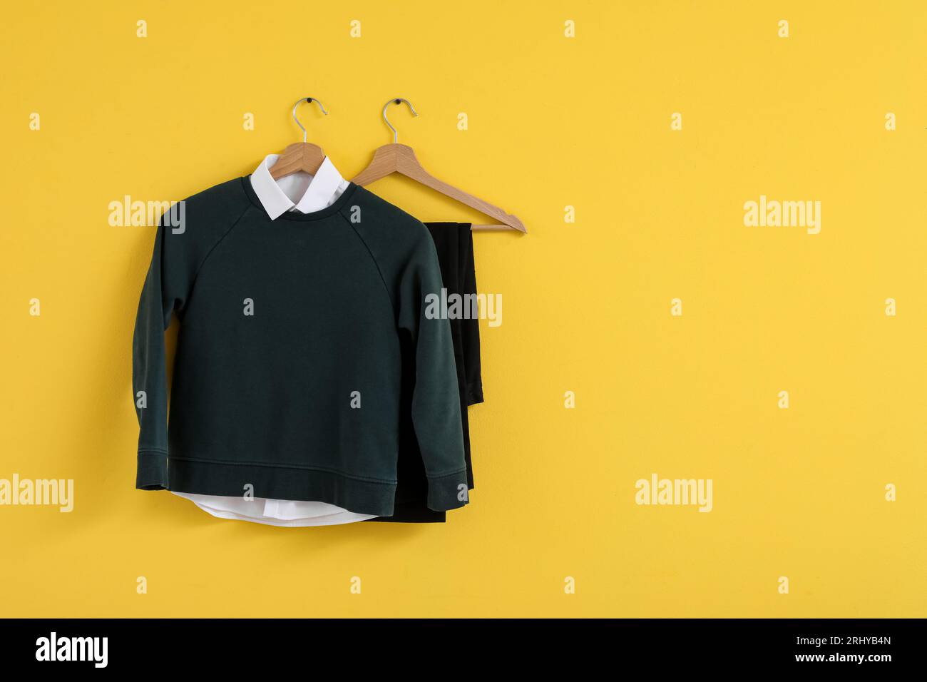 Stylish school uniform hanging on yellow wall Stock Photo Alamy