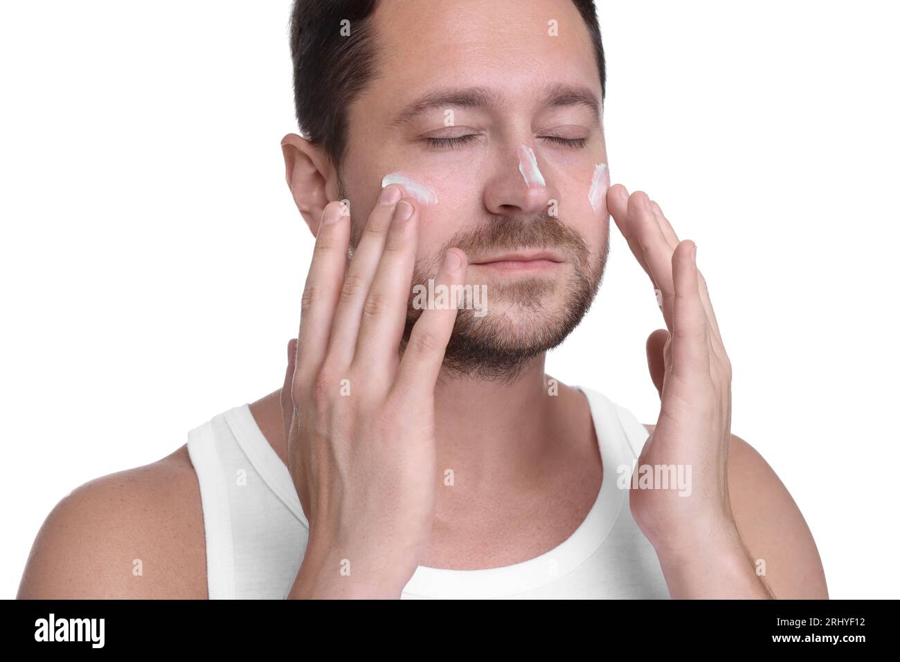 Man applying sun protection cream onto his face against white