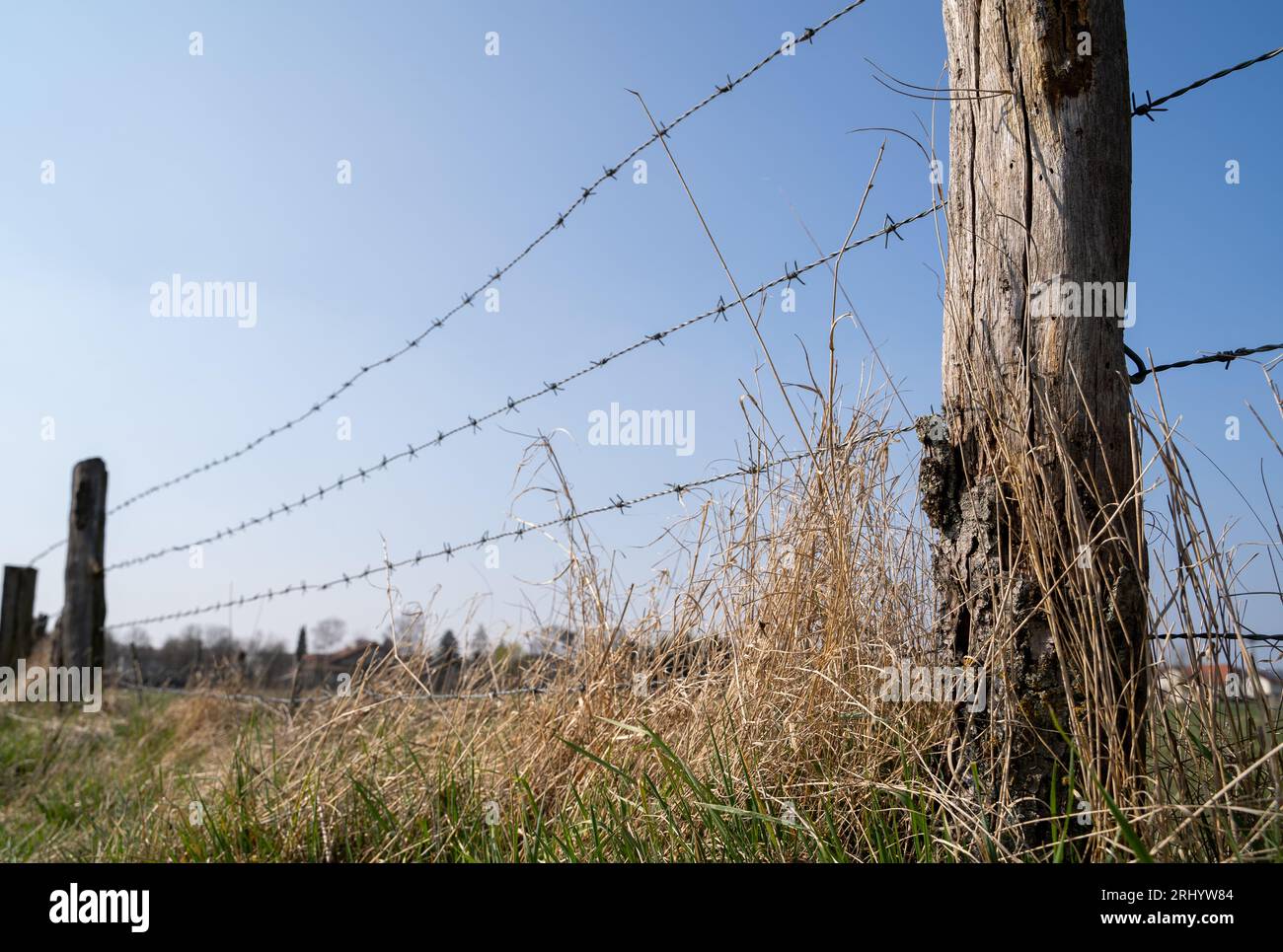 Fence with wooden post and barbed wire in the landscape on a sunny ...