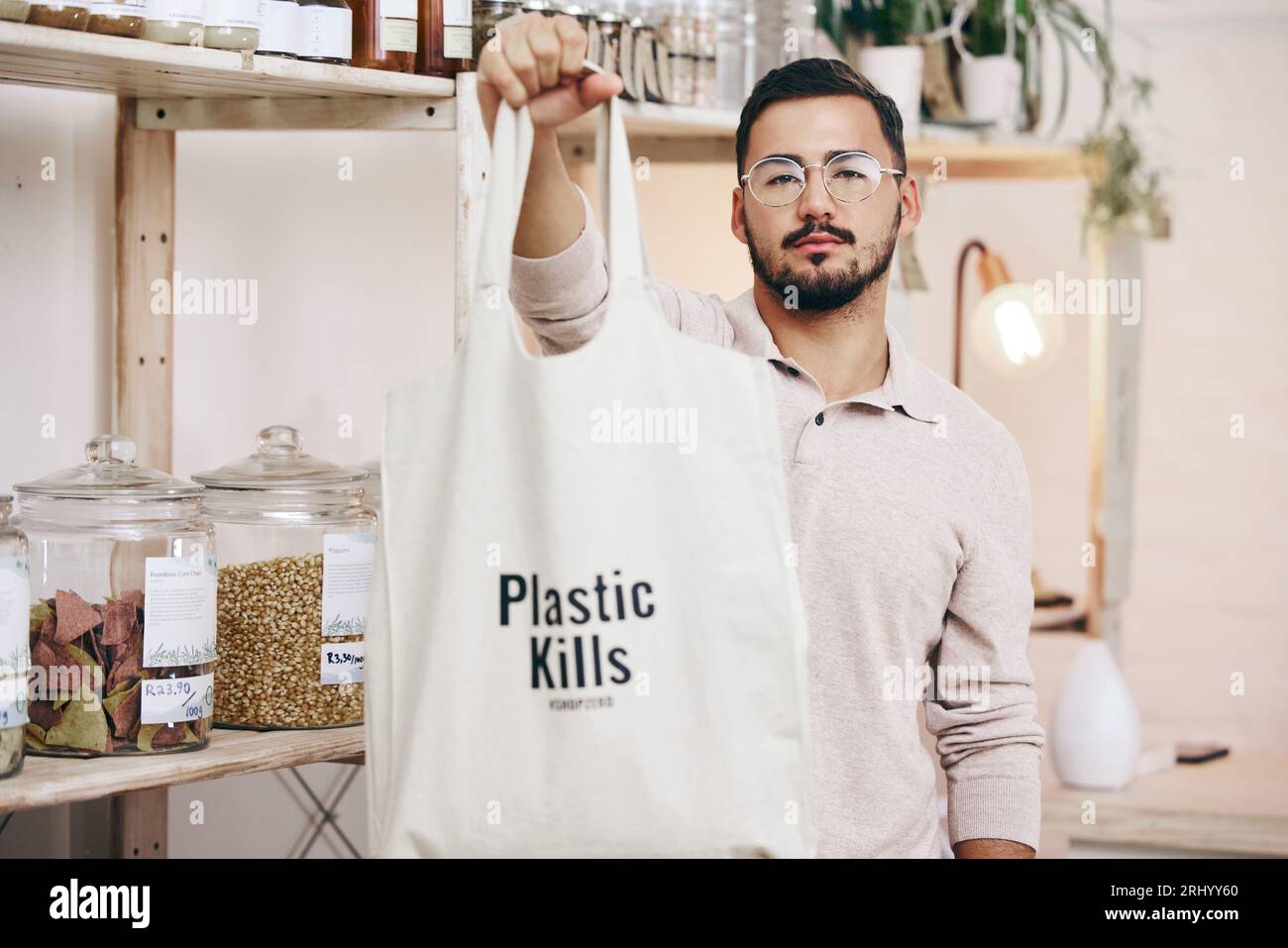 Man at eco friendly grocery store, fabric shopping bag and commitment to climate change at sustainable small business. Zero waste, plastic kills logo Stock Photo