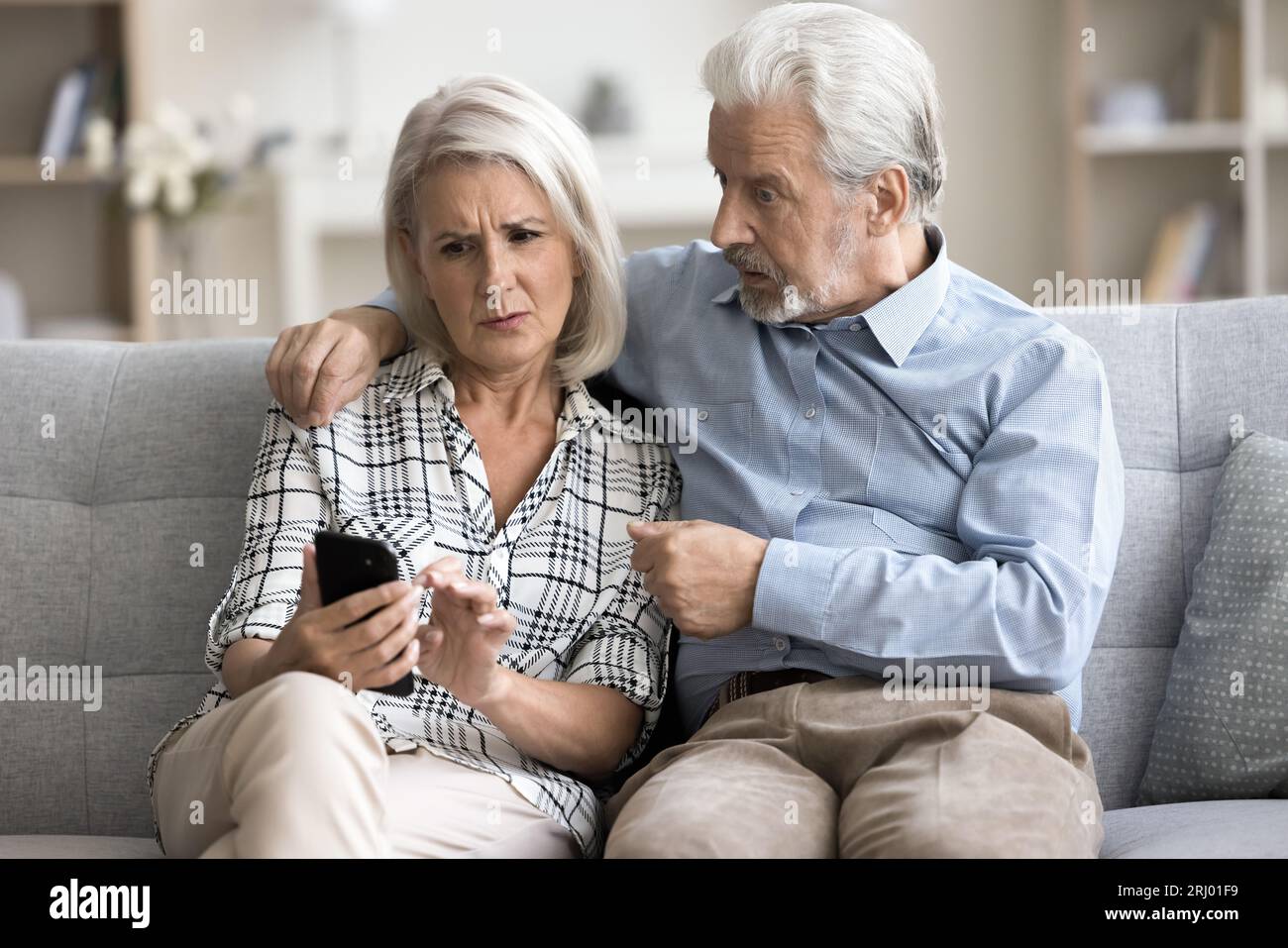 Anxious concerned older couple using mobile phone together Stock Photo