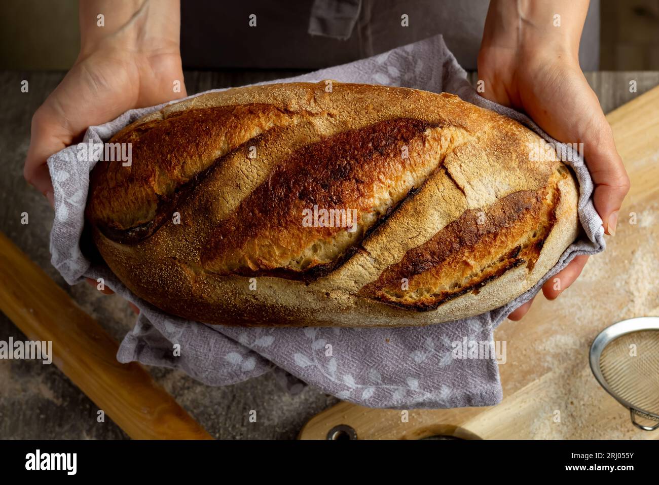 Close-up of freshly baked bread in hands on a wooden board background. Stock Photo
