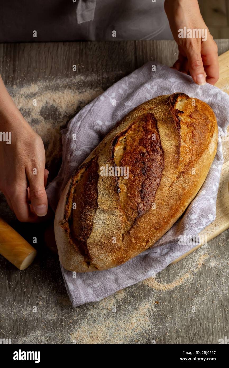 Close-up of freshly baked bread in hands on a wooden board background. Stock Photo