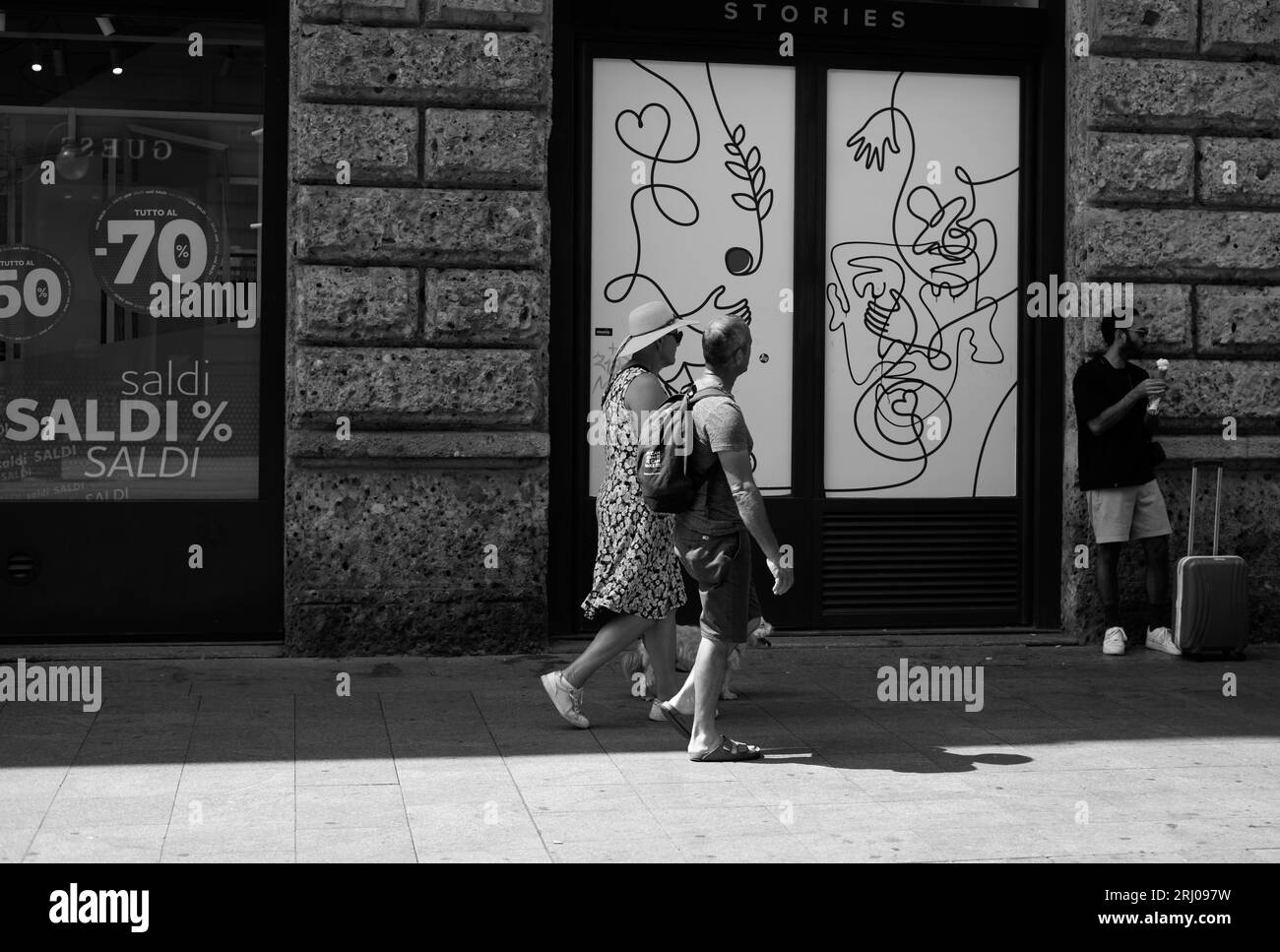 couple walking in front of boutiques in downtown milan Stock Photo