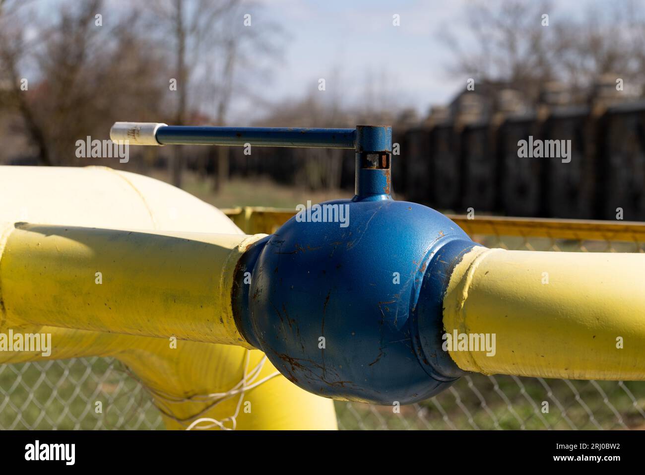 Yellow gas pipe with valve. Transportation, delivery of gas to consumers. Manual shut-off valve service with pipeline gas. Gasification land plots. Th Stock Photo
