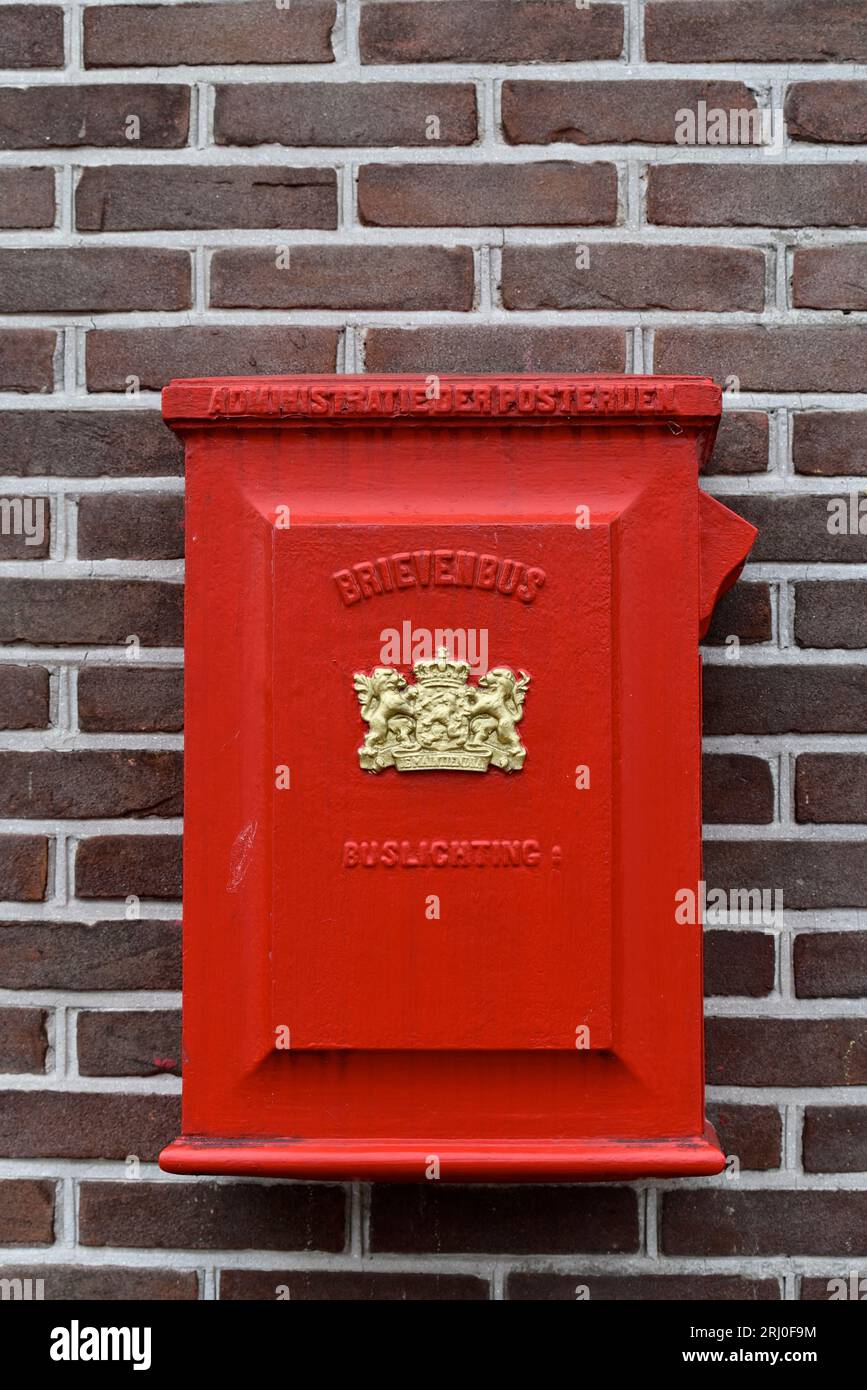 Nostalgic red mailbox against brick wall in the center of Spakenburg; coat of arms with the text je maintiendrai Stock Photo