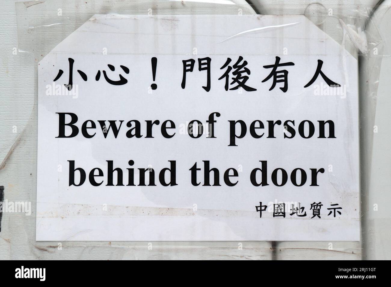 Bilingual Warning, 'Beware of person behind the door', sign at construction works at Caine Road Playground, mid-levels, Hong Kong Island,  20 Aug 2023 Stock Photo