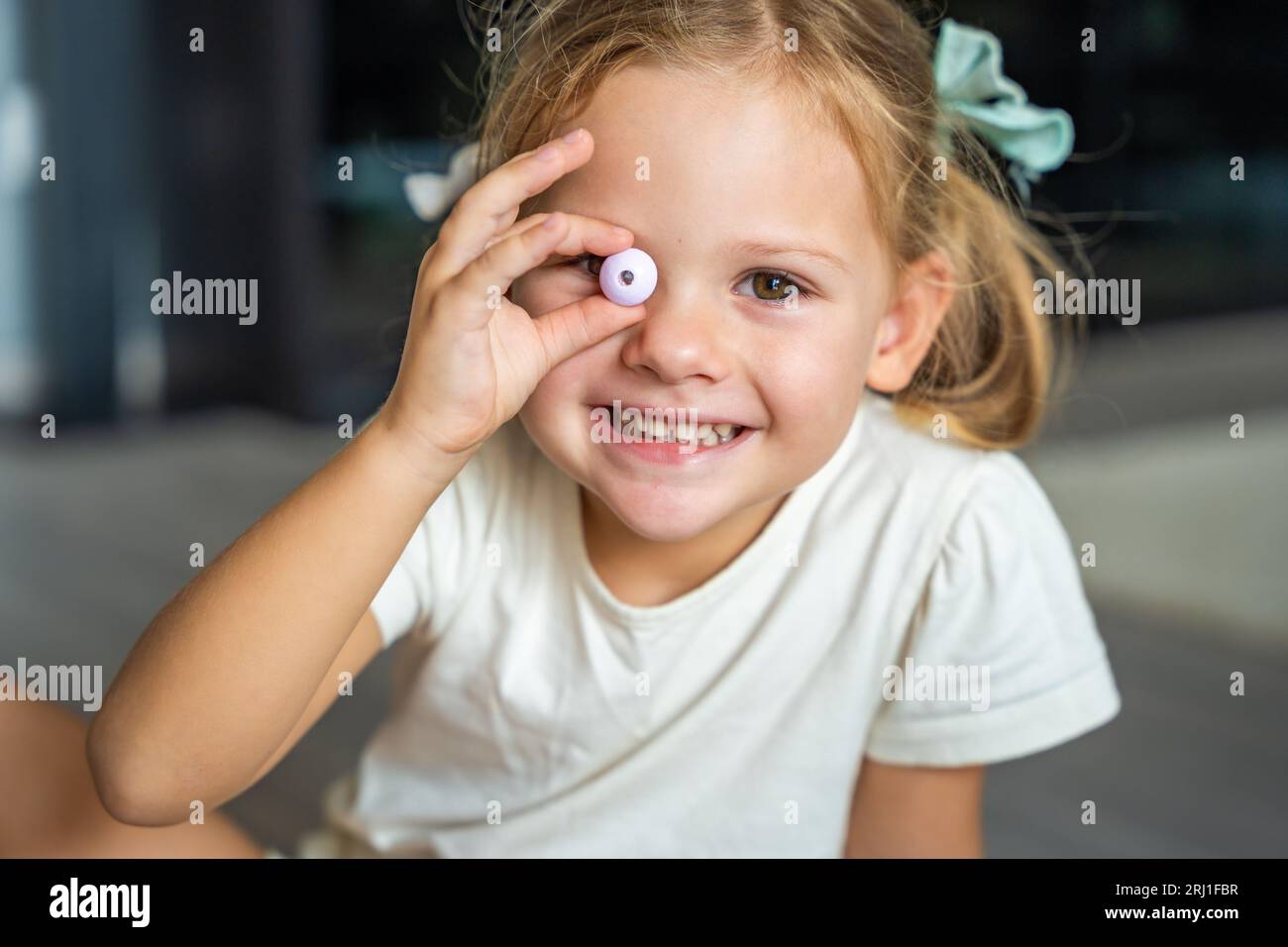 Little girl plays with bead making wooden beads bracelet. Children's