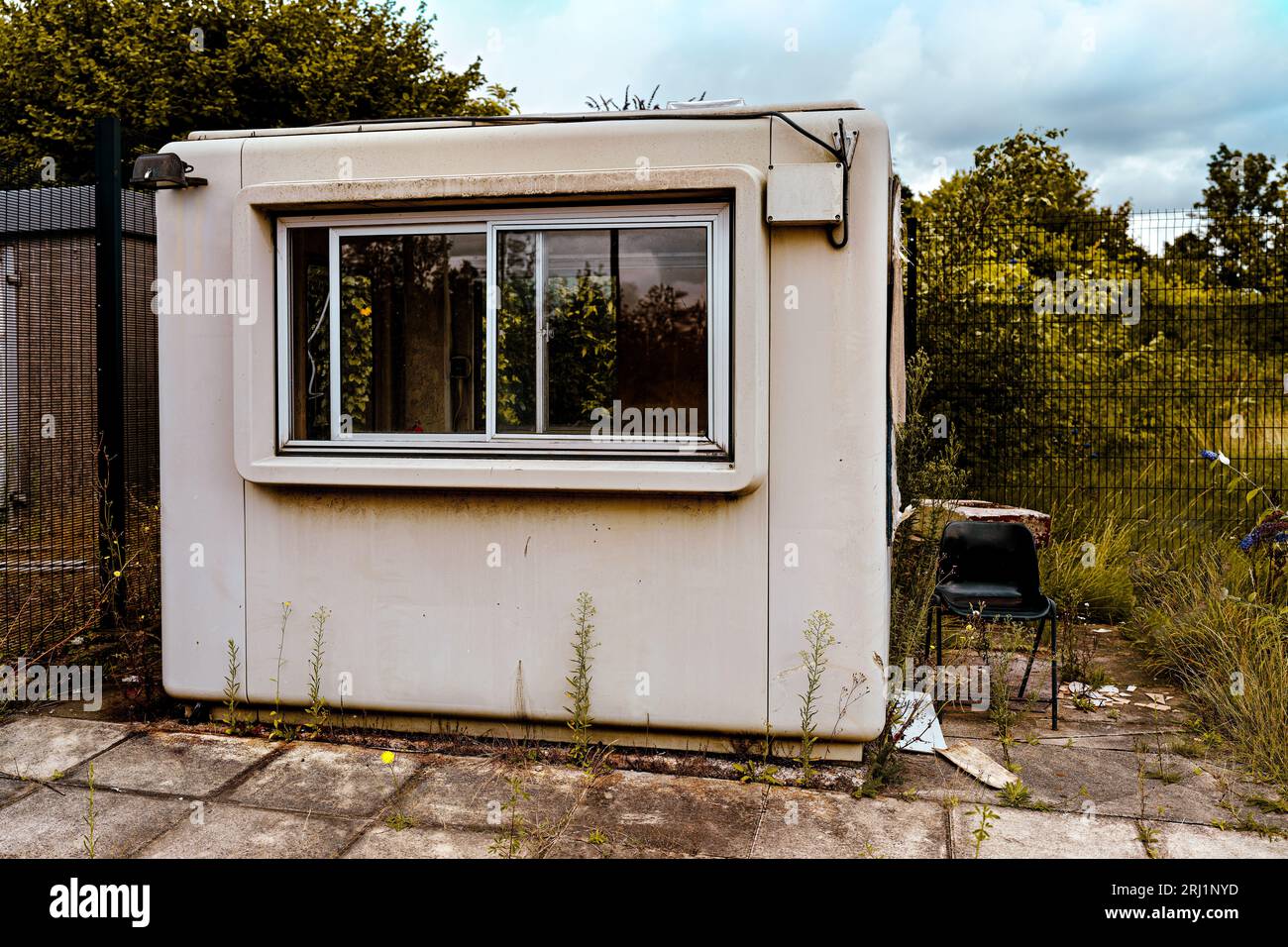 unused site office in decay with old black plastic chair outside the door, left to rot and decay Stock Photo