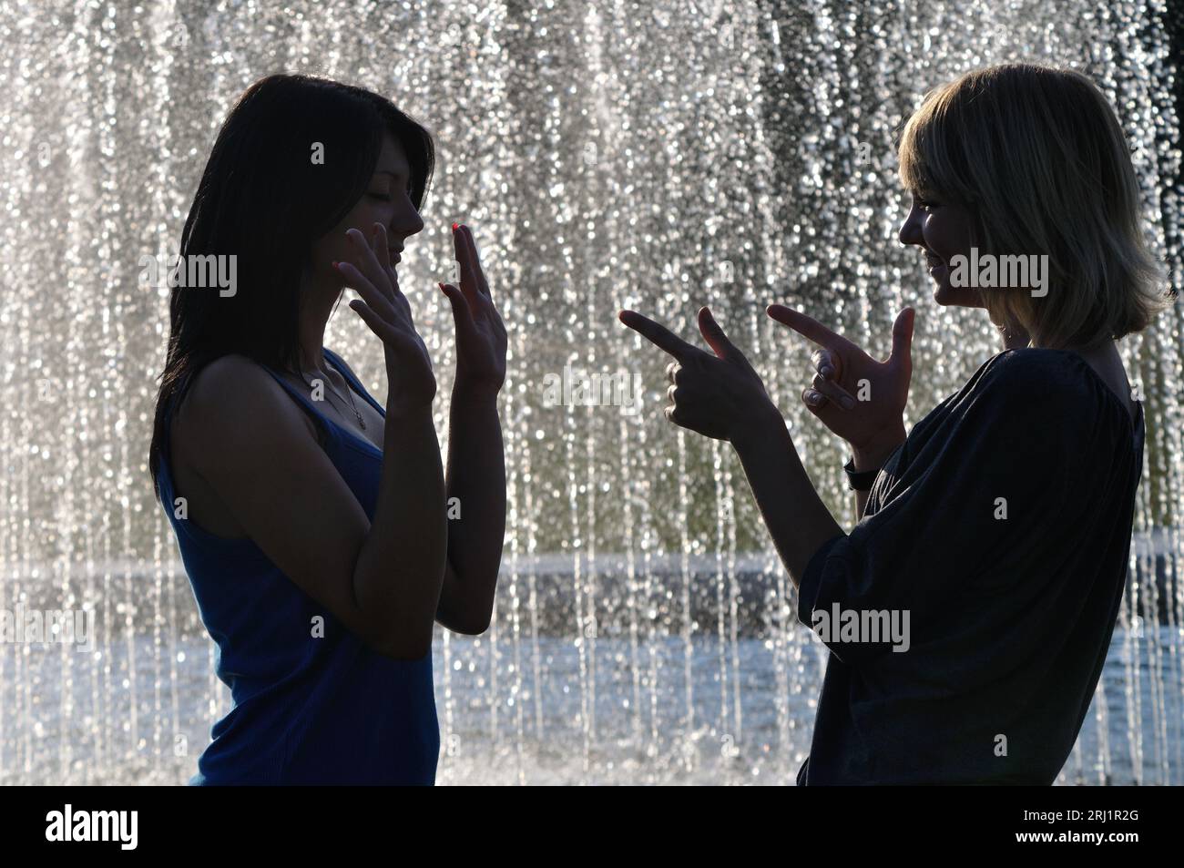 Cherkasy, Ukraine- June 11, 2011.  Happy unidentified young women are meeting near the fountain  at hot day, backlit Stock Photo