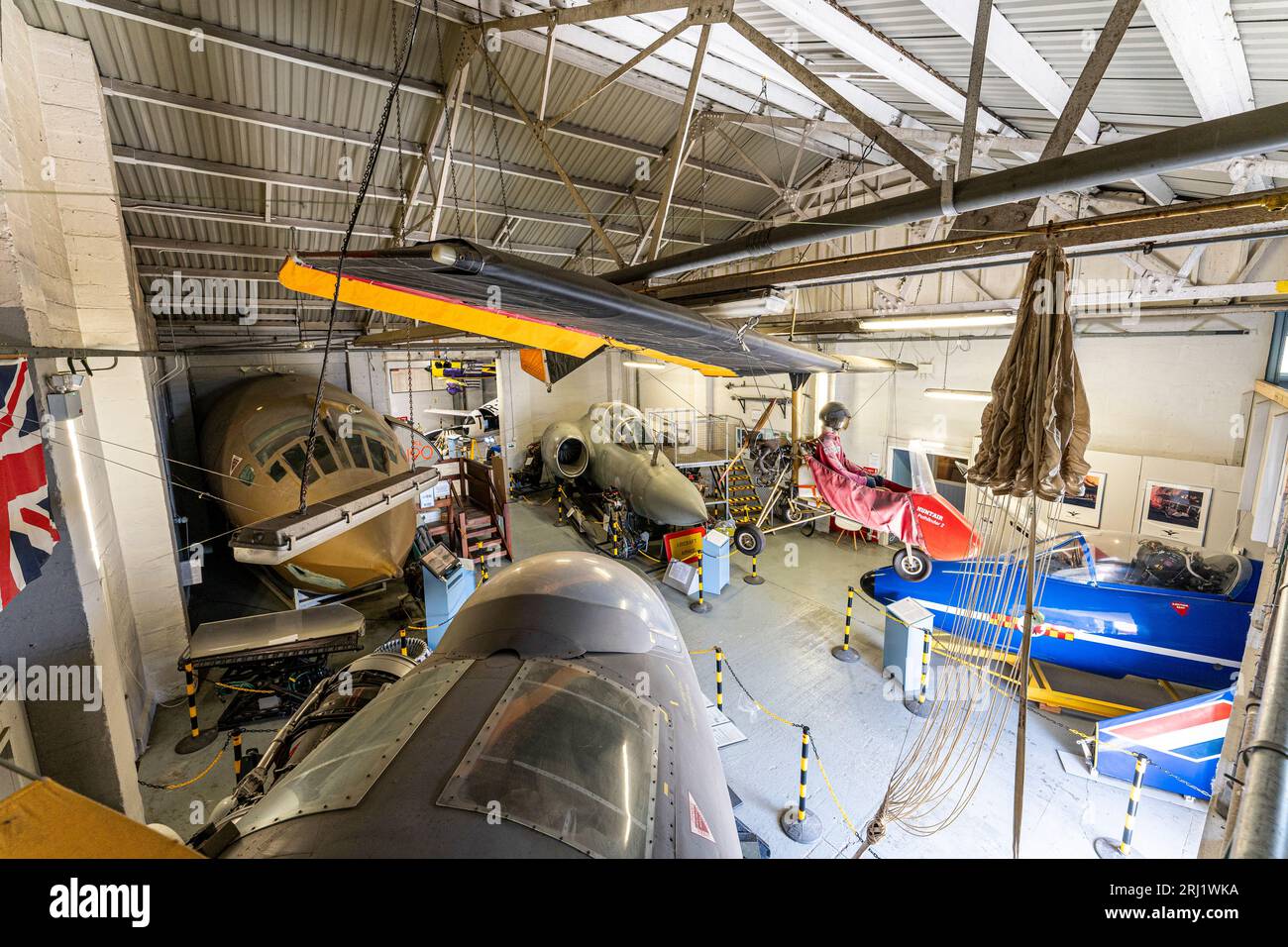 Interior, hanger at RAF Manston museum with a Pathfinder microlight hanging from ceiling, cockpit sections of a Victor bomber, Canberra and Buccaneer. Stock Photo