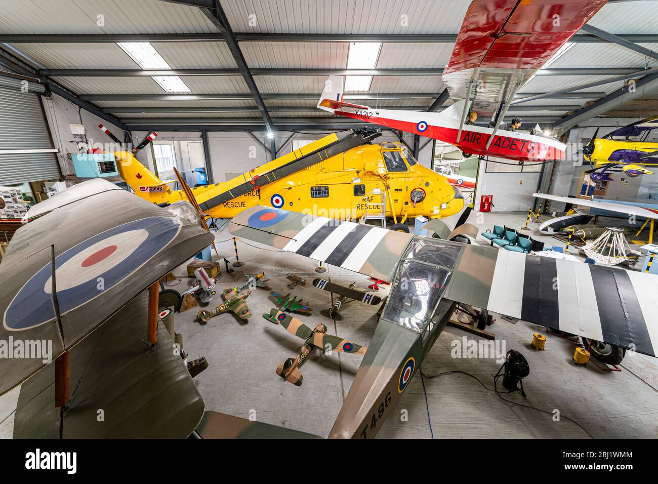 Interior, hanger at RAF Manston museum with a Slingsby trainer glider hanging from ceiling, and an Auster spotter plane and Westland Wessex chopper. Stock Photo