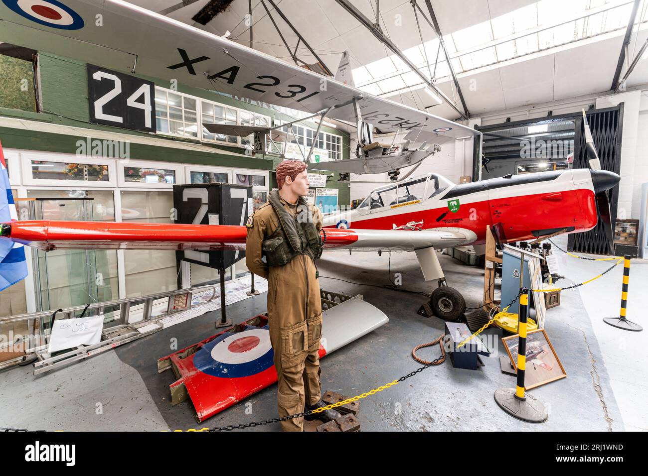 De Havilland Chipmunk trainer plane with pilot figure next to it, and above, suspended from the ceiling, a Slingsby Grasshopper glider. Manston museum Stock Photo