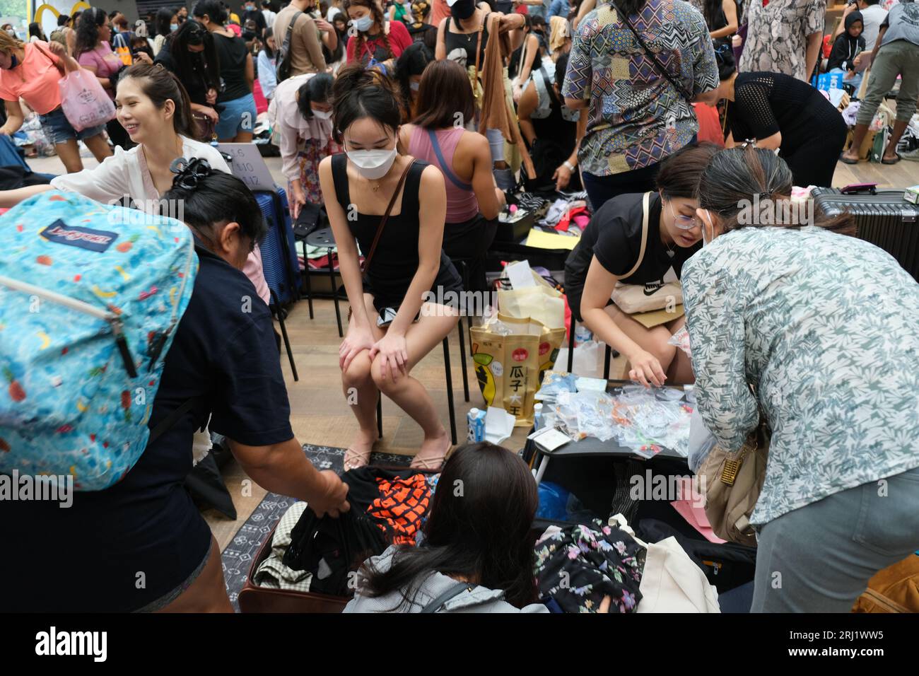 Young women sell cheap secondhand clothes to people including Filipino maids on their day off at a thrift market in Singapore's Aperia Mall. 18/09/202 Stock Photo