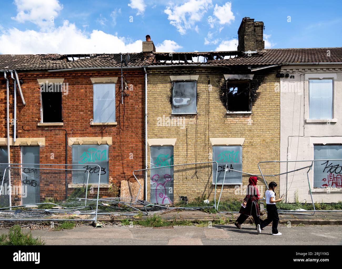 BRADFORD, UK - AUGUST 16, 2023. A row of burnt out and derelict terraced houses in a poor Asian community in the North of England with boarded up wind Stock Photo