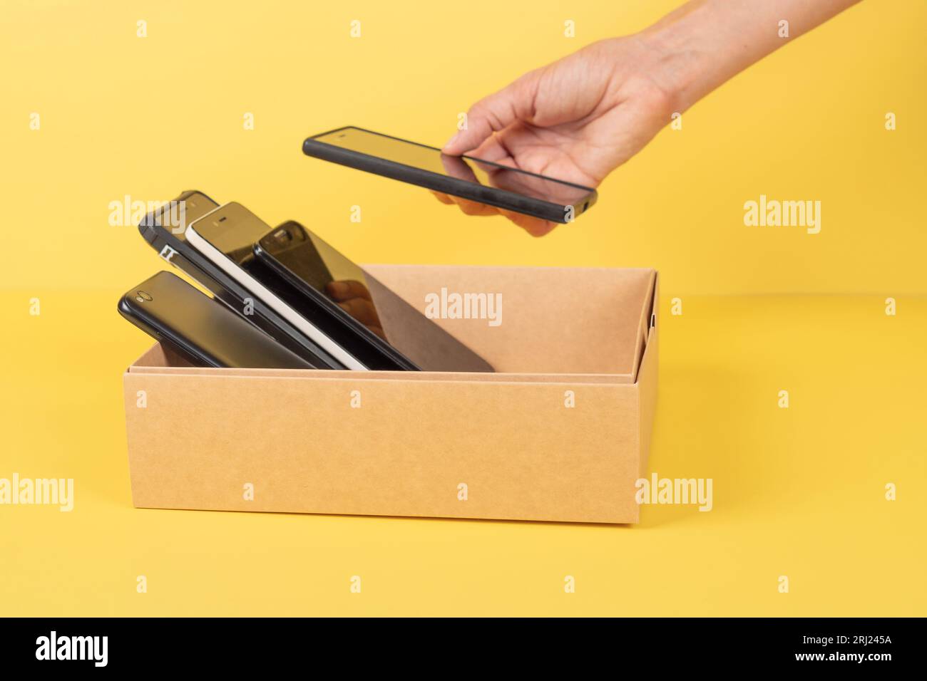 Donations of used cell phones. Hand put old cell phone to cardboard box