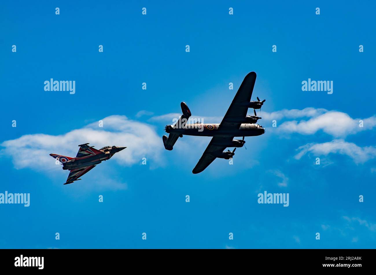 A modern RAF Typhoon fighter bomber and a World War Two-era Lancaster heavy bomber fly past the seafront at the annual Eastbourne Airbourne, an intern Stock Photo