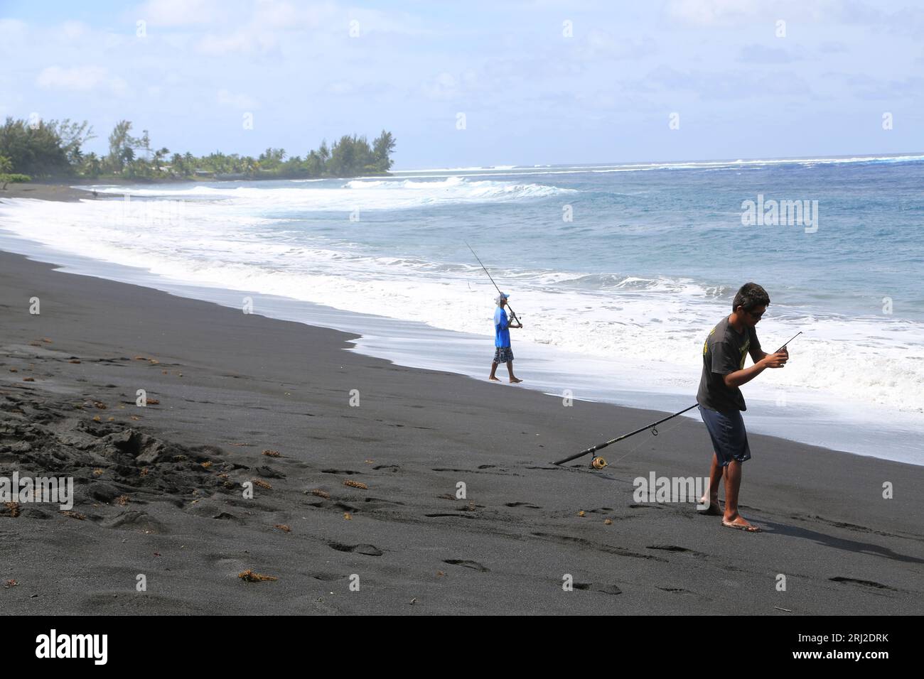Pêche à la ligne sur la plage de sable noir volcanique de Papara à Tahiti en Polynésie française. Cette plage de Taharuu est connue pour ses belles va Stock Photo
