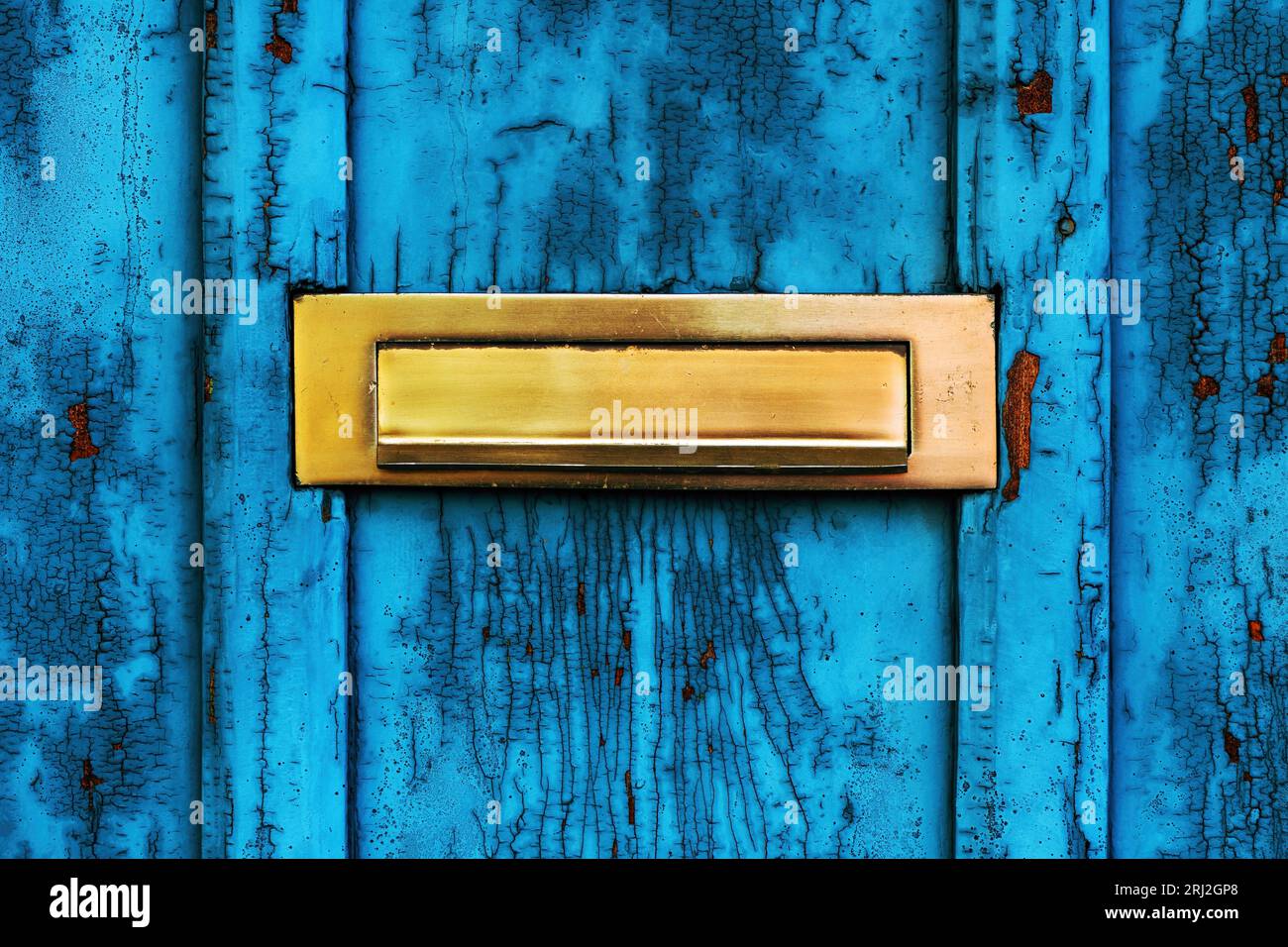 Old letterbox or mailbox slot on worn wooden blue door with paint