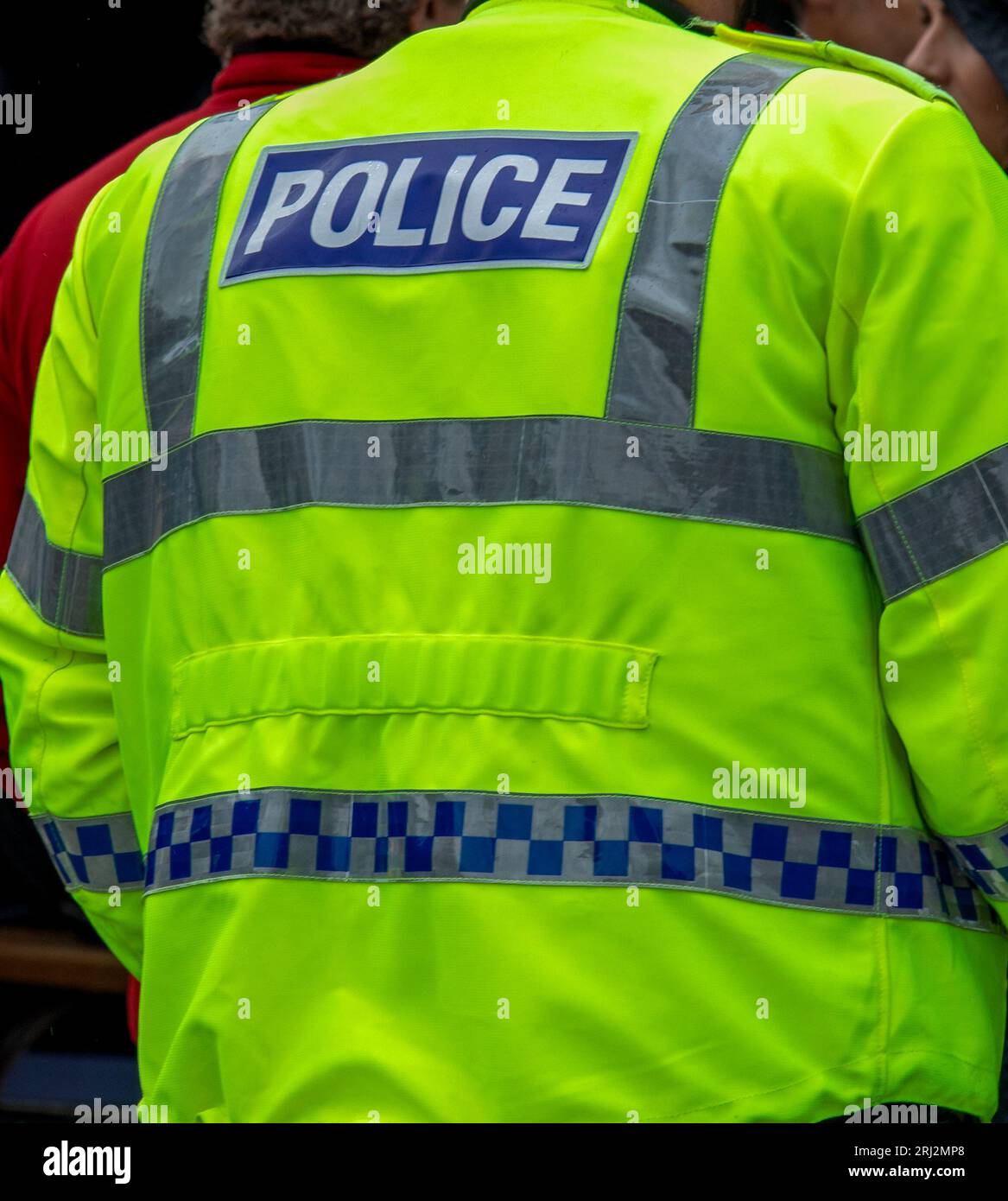 Bright yellow high visibility jacket police uniform worn by an on duty police officer Stock Photo