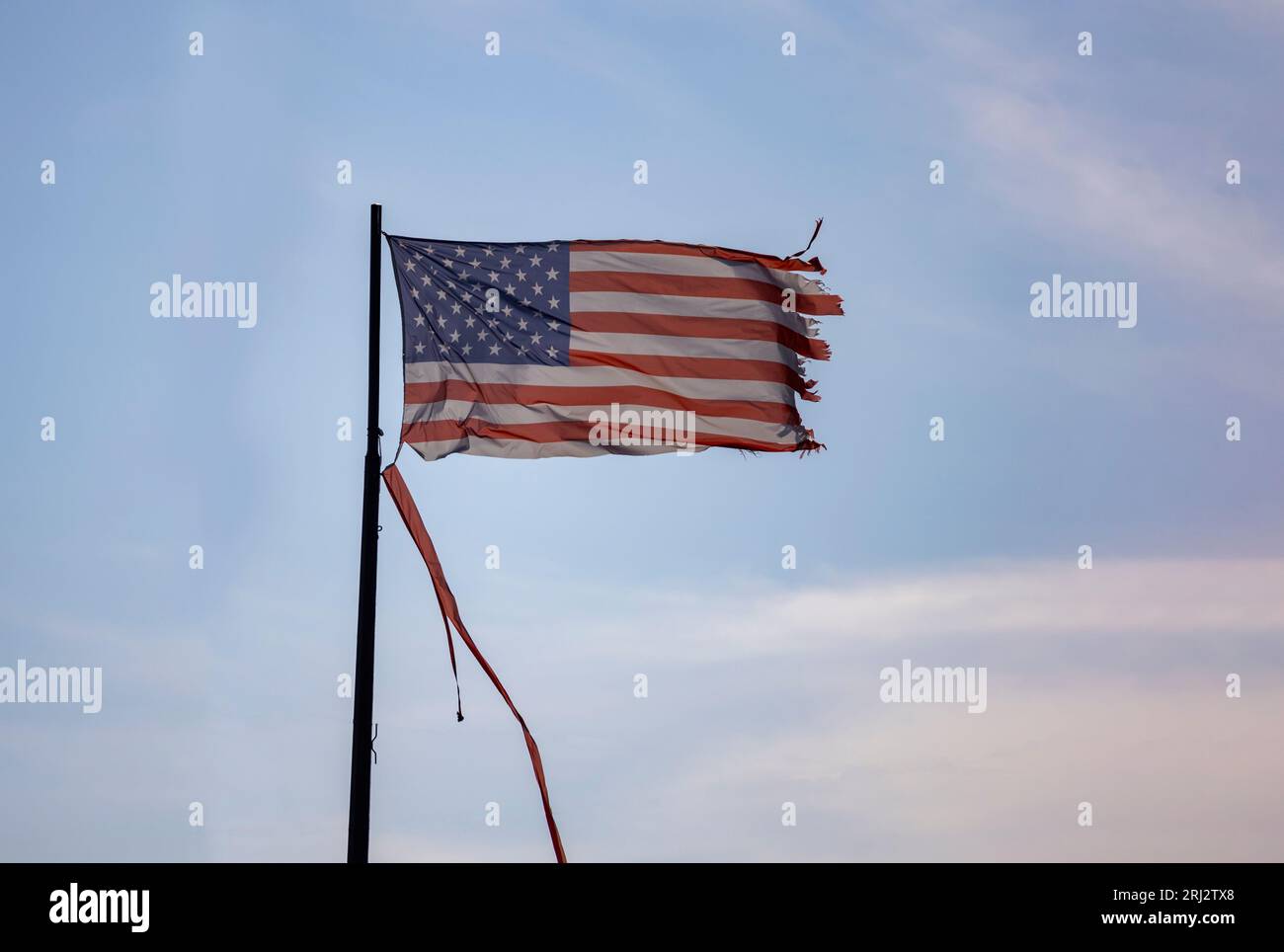 A Weathered and Torn American Flag blowing in the wind Stock Photo