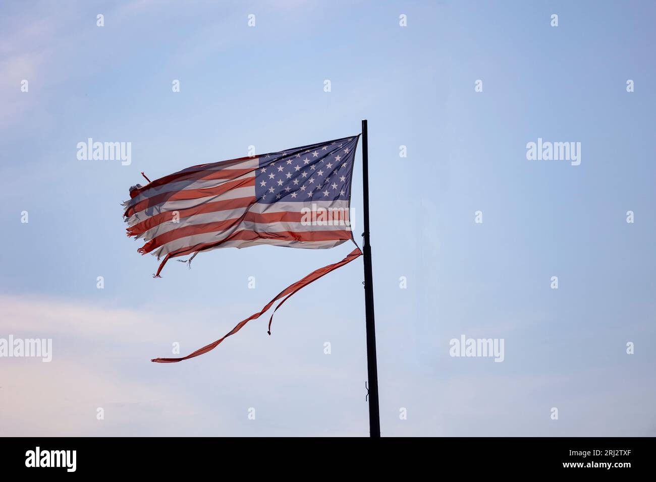 A Weathered and Torn American Flag blowing in the wind Stock Photo