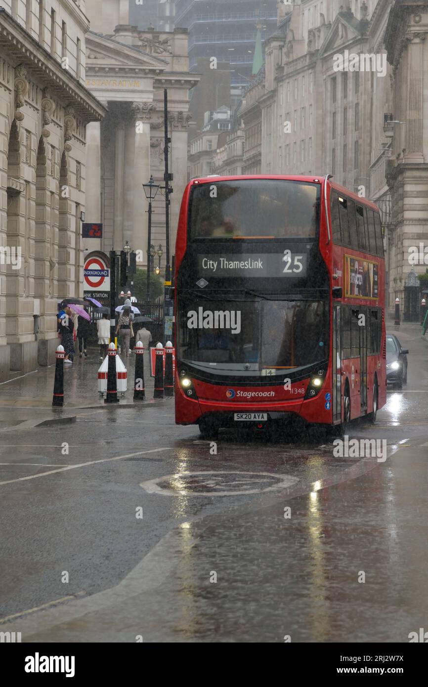 London, UK - July 30, 2023; London red double decker bus in pouring summer rain on city street with headlights reflecting in the water Stock Photo