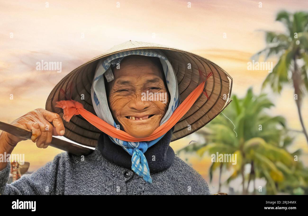 Hoi-An, Vietnam - December 9. 2001: Portrait of old hard working poor smiling farmer woman with traditional cone hat carrying heavy loads with stick ( Stock Photo