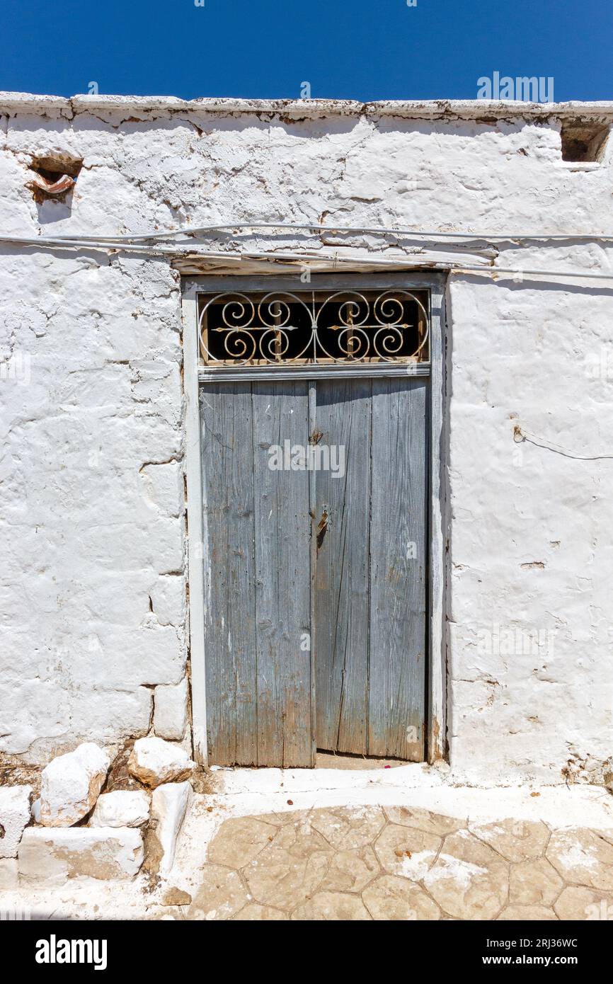 Traditional old wooden door of a typical house with white washed walls in the Old Town of Aegina island, in Saronic Gulf near Athens, Greece, Europe. Stock Photo