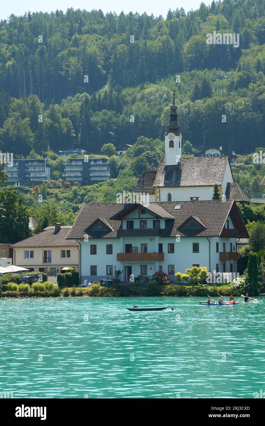A stunning aerial view of a beautiful house, situated by a tranquil lake surrounded by lush green forests in the Carinthia region of Austria Stock Photo