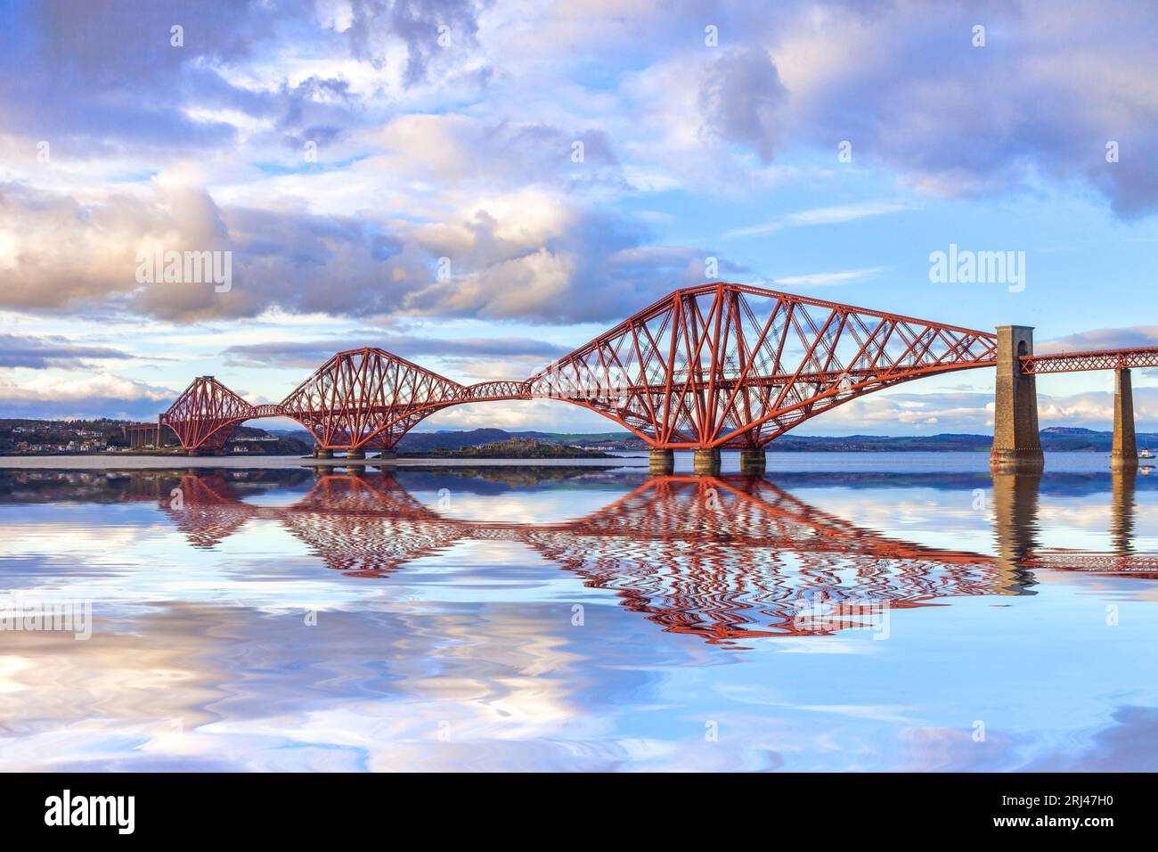 The Forth Rail Bridge, one of Scotland's most famous landmarks, with a reflection in the Firth of Forth.  Designed by engineers Sir John Fowler and... Stock Photo