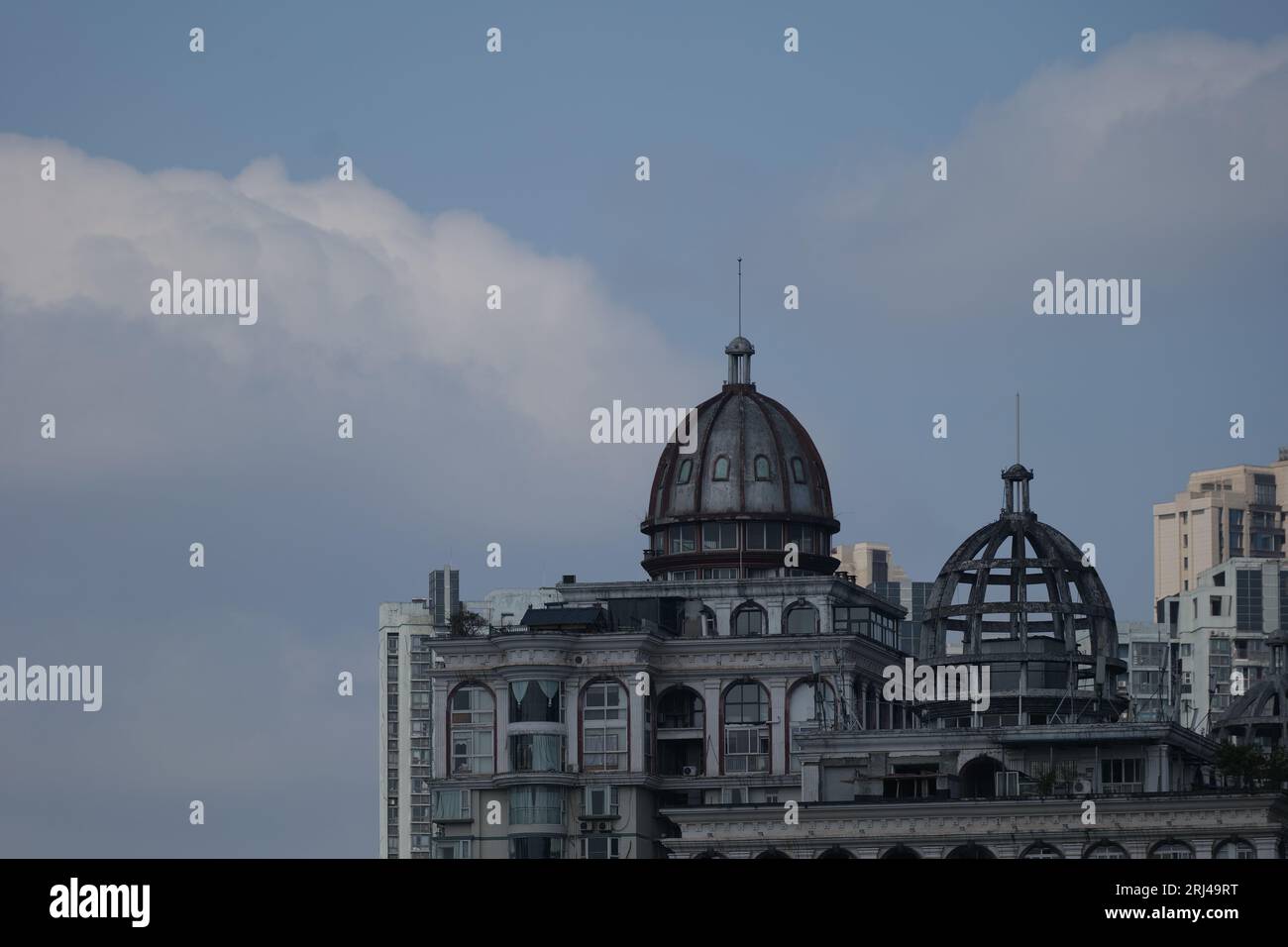 An old weathered building with a domed roof in the city skyline Stock Photo