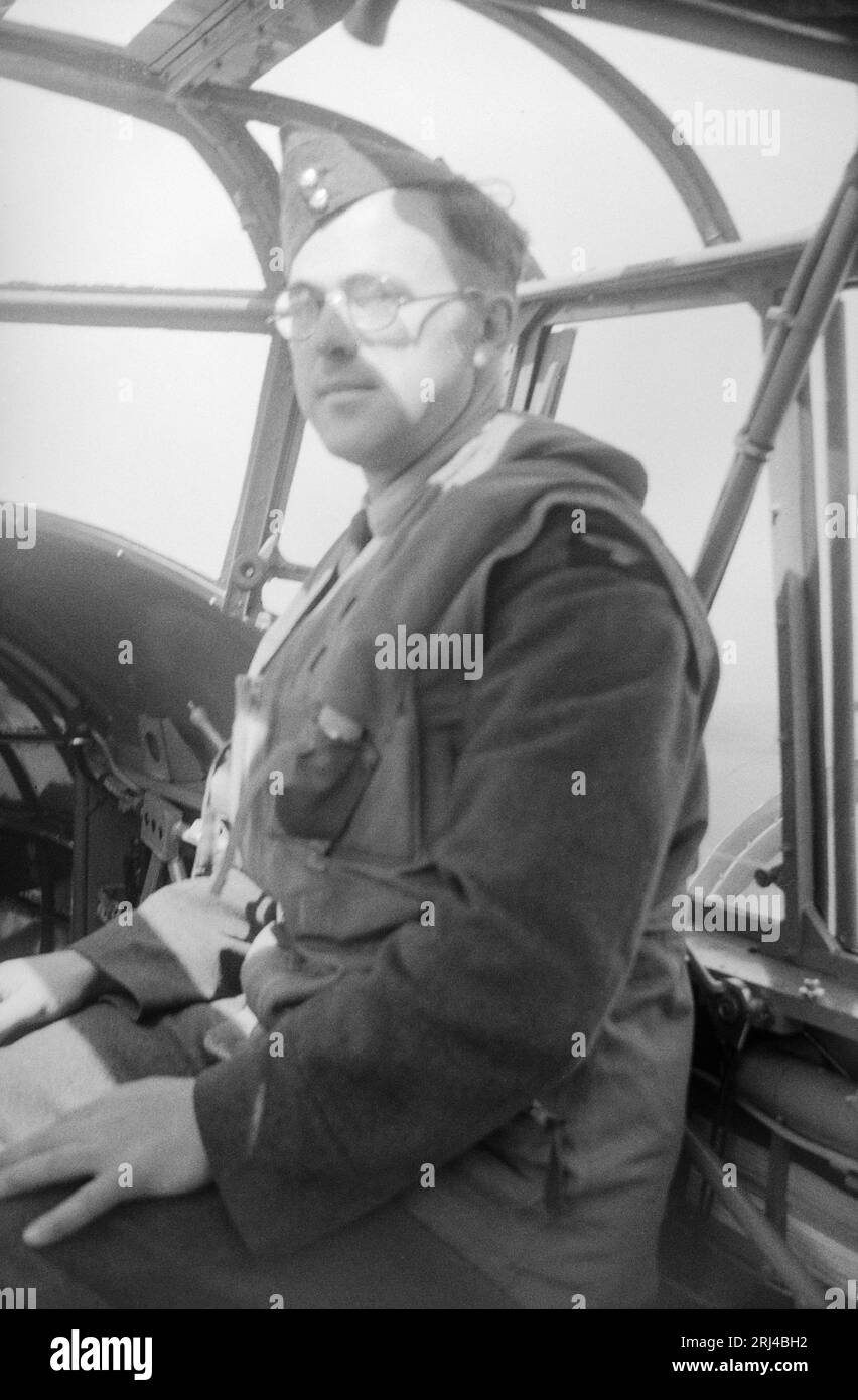 A 1930s black and white photograph showing an Airman of The Royal Air Force, posing for the camera, whilst flying in a military aircraft. Stock Photo