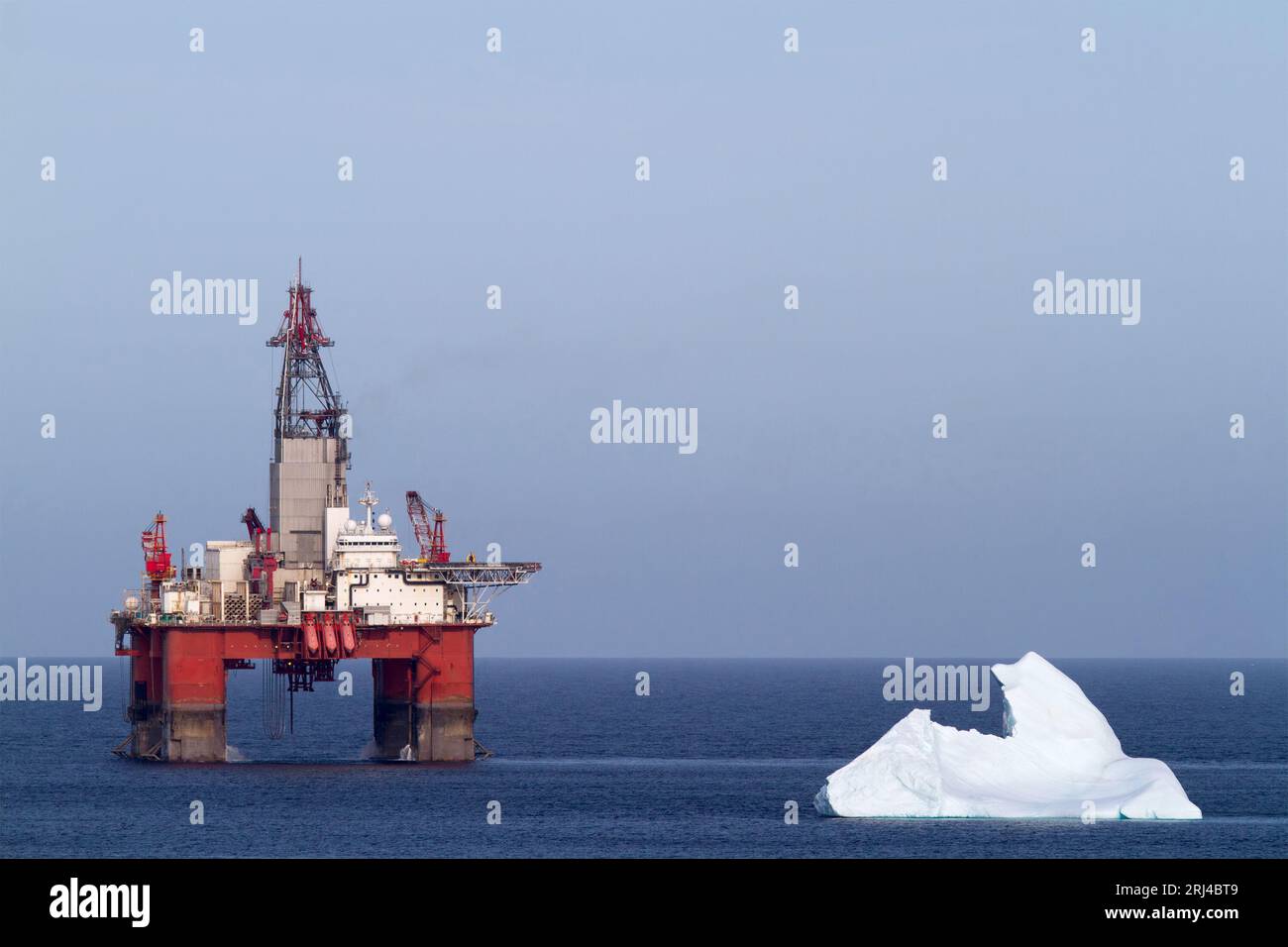 An offshore oil rig on the surface of blue water in the ocean with a ...