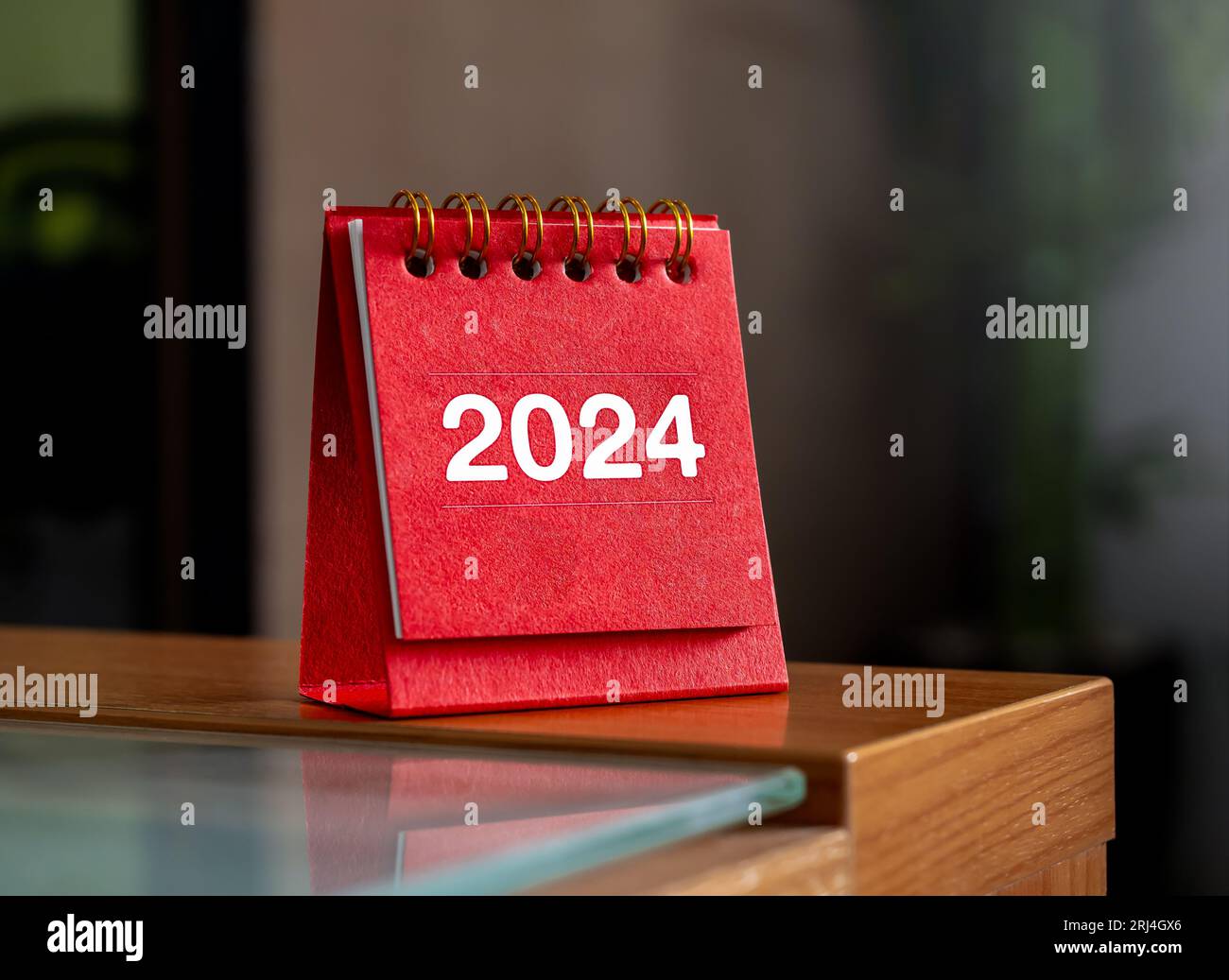 Happy new year 2024 banner background. 2024 numbers year on red spiral small desk calendar cover standing on table with copy space. Business goals and Stock Photo