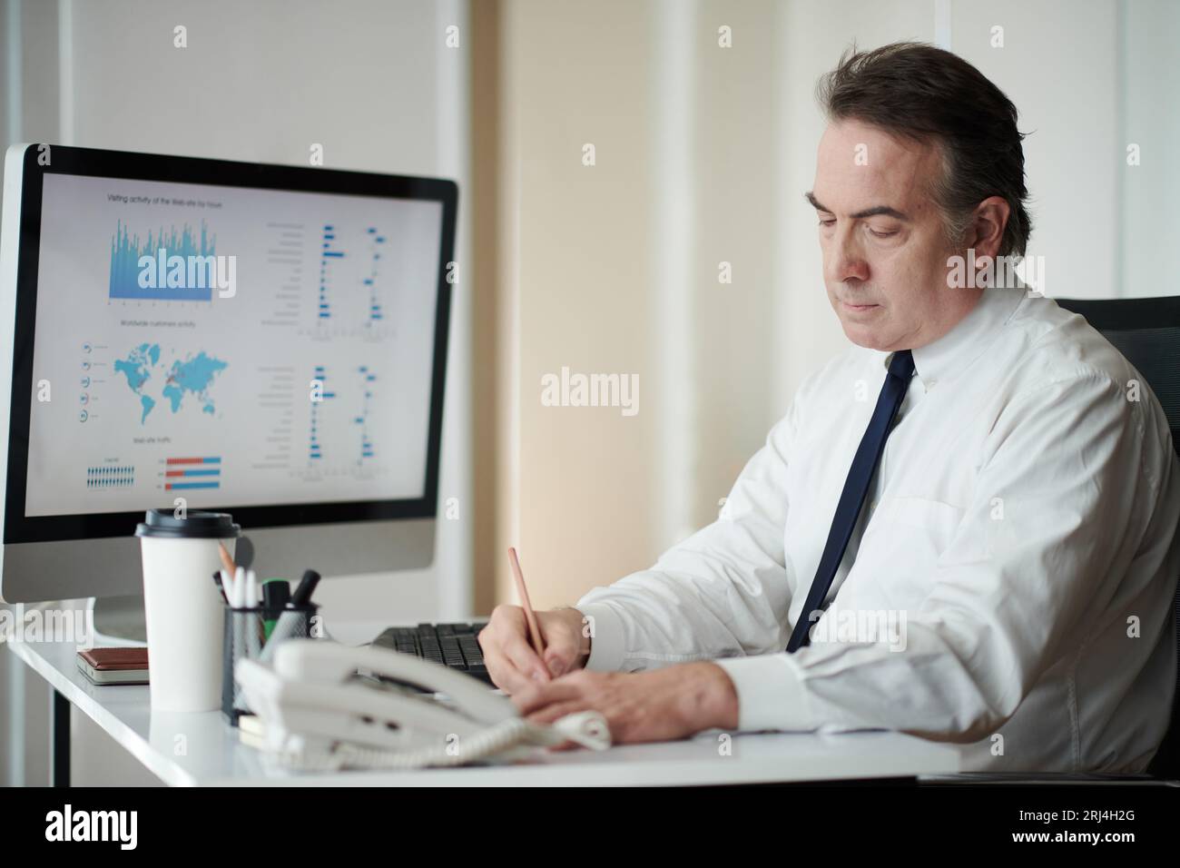 Concentrated mature entrepreneur analyzing chart on computer screen and ...