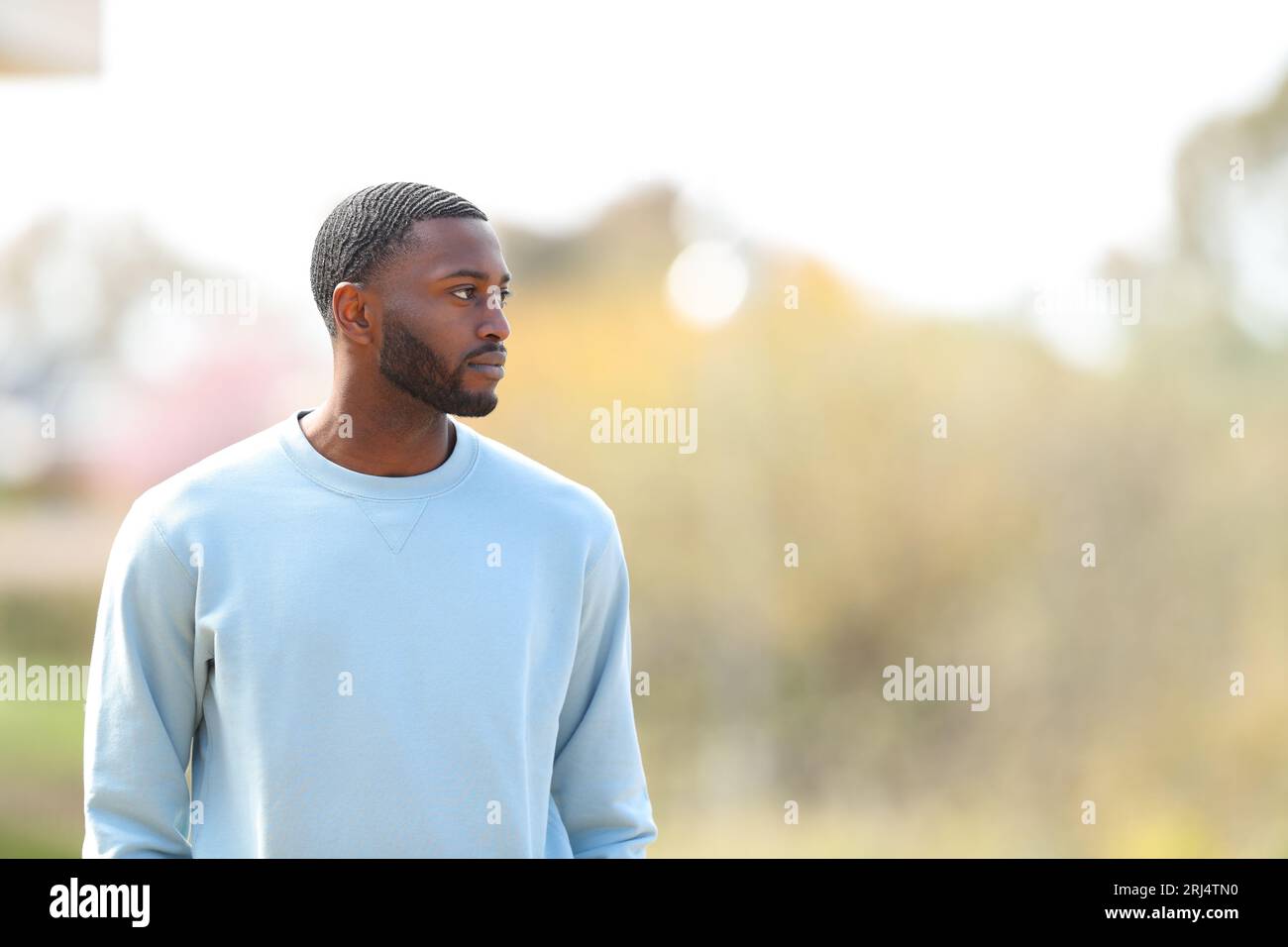 Serious black man walking alone in a park Stock Photo - Alamy