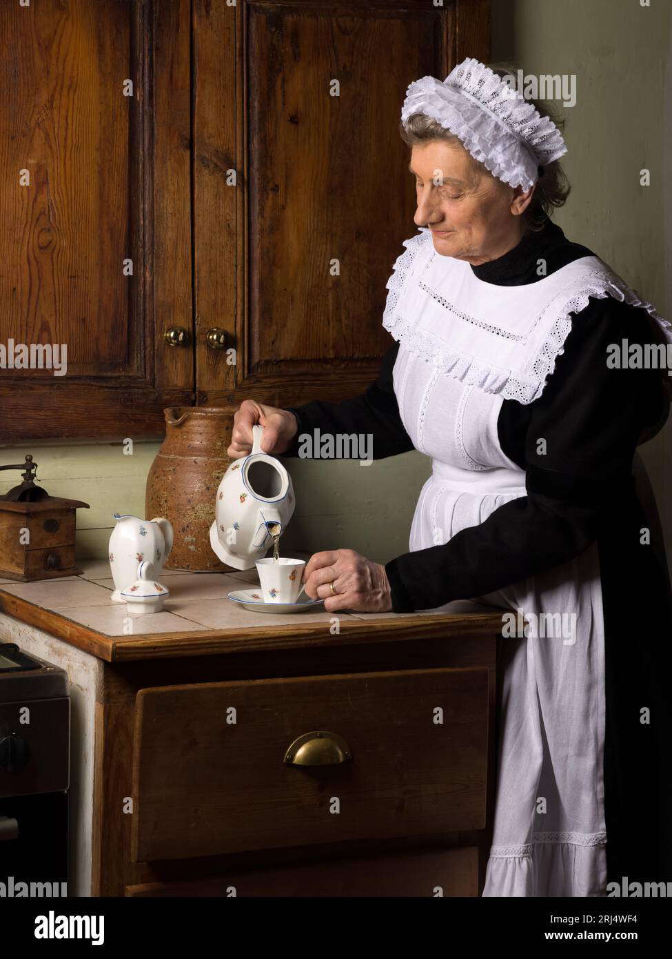 https://c8.alamy.com/comp/2RJ4WF4/victorian-maid-or-servant-in-black-dress-lace-cap-and-white-apron-working-in-a-19th-century-interior-2RJ4WF4.jpg