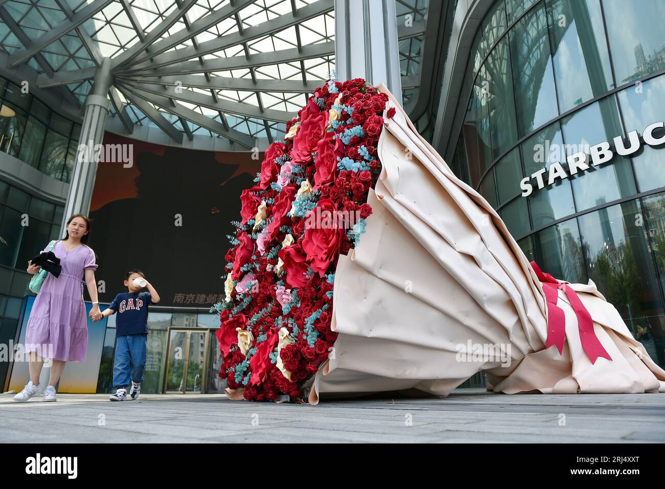 NANJING, CHINA - AUGUST 21, 2023 - Citizens walk past a 'rose' installation held in Nanjing, Jiangsu province, China, Aug. 21, 2023. August 22 is Chin Stock Photo